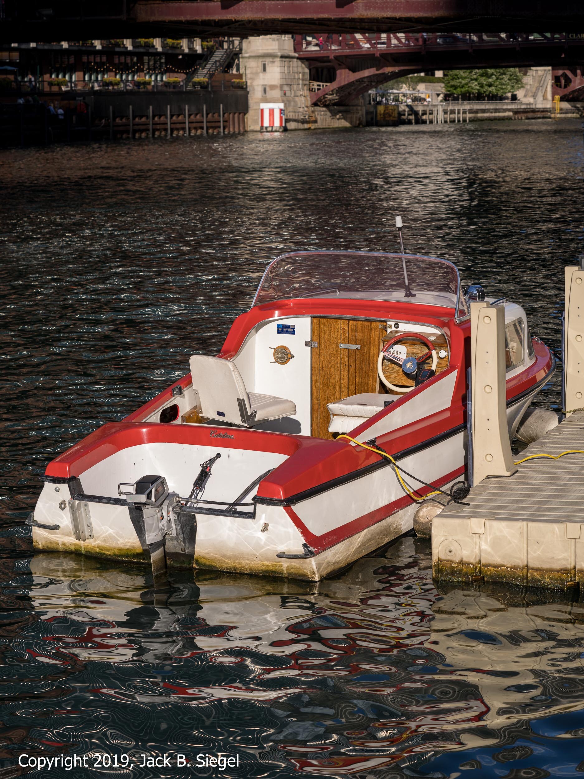 A Classic Motorboat from the Sixties is Docked at the River Walk, with the Sun Still Casting Its Warm Light
