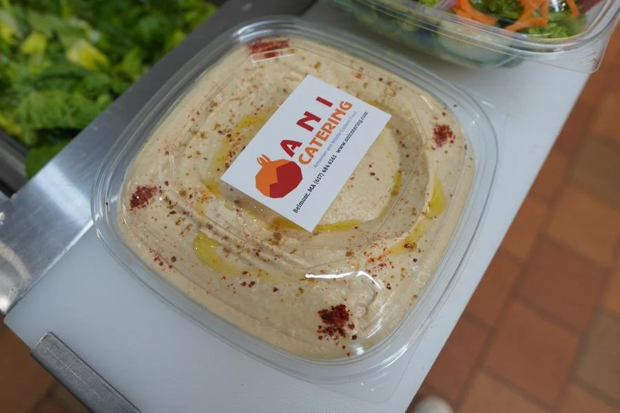 Container of hummus with olive oil and aleppo red pepper from ANI Catering chicken kabob platter