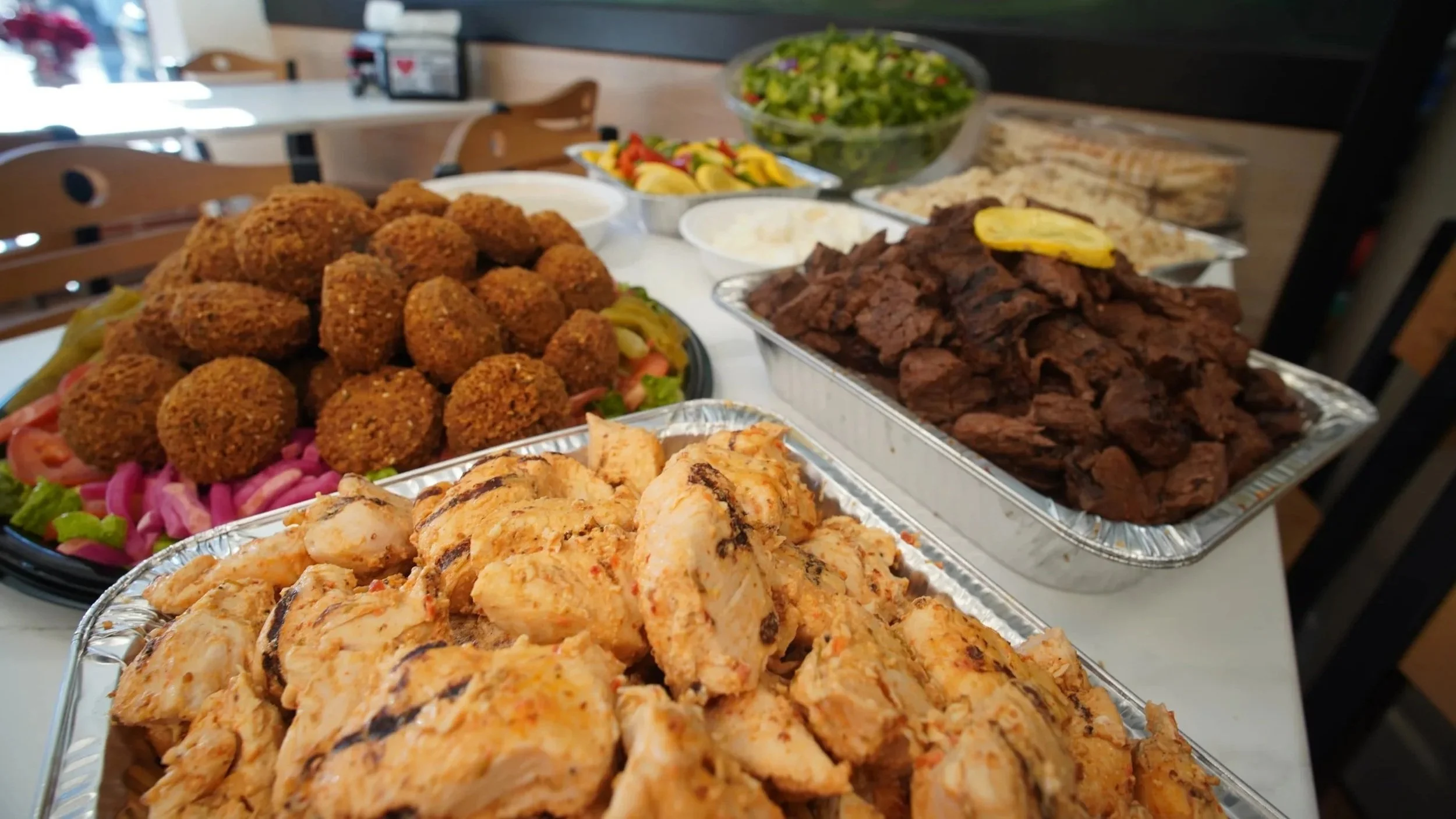 ANI Catering graduation party spread with falafel platter, halal grilled lamb, halal chicken shawarma, rice pilaf, roasted vegetables, garden salad, and fresh lavash — graduation party catering services Boston