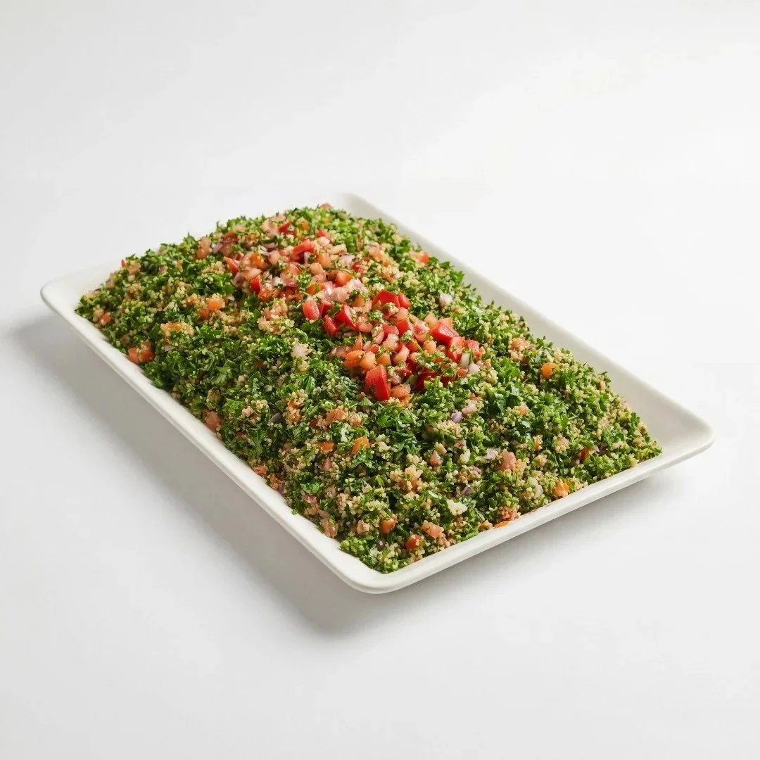 Large serving tray of fresh tabbouleh salad with finely chopped parsley, bulgur, tomato, and red onion
