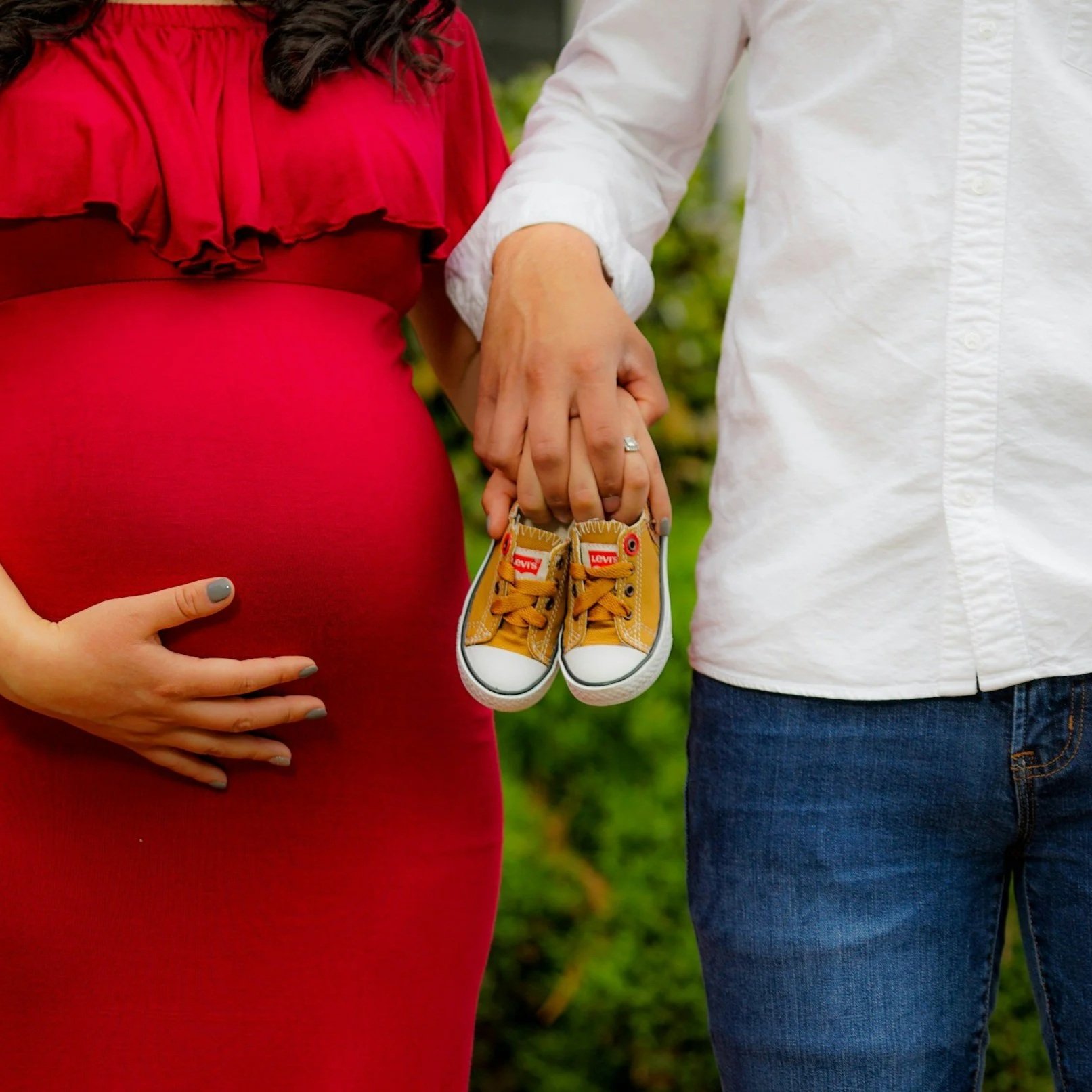 Expecting couple holding tiny baby sneakers, representing a baby shower celebration catered by ANI Catering in Boston