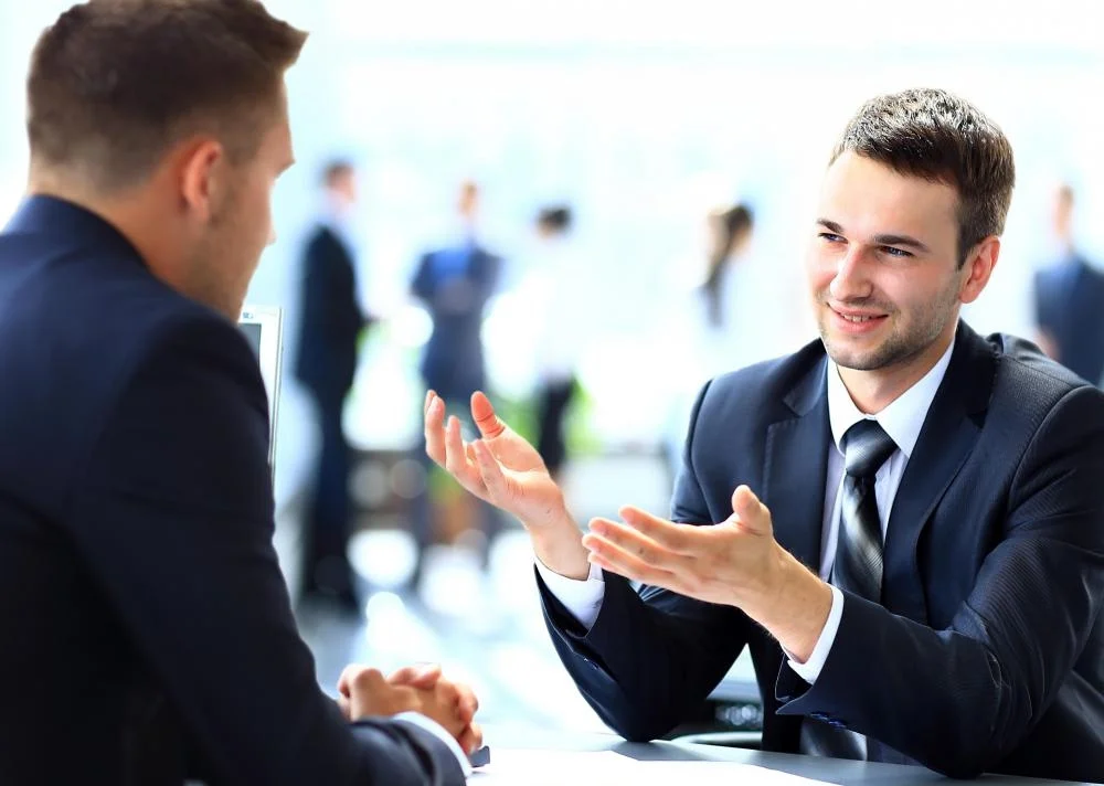 man-in-business-suit-talking-to-man-in-front-of-him.jpg