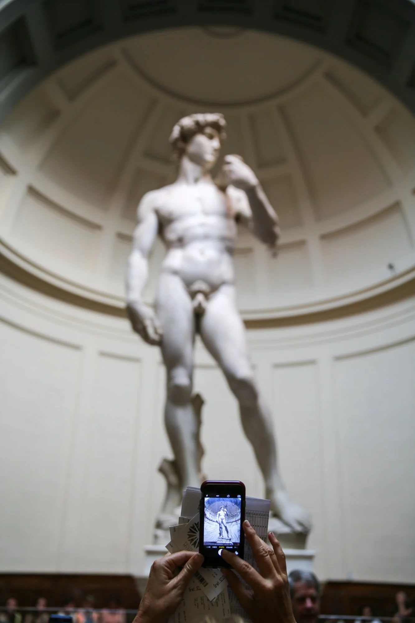 Visitor photographing Michelangelo’s David sculpture in a museum gallery