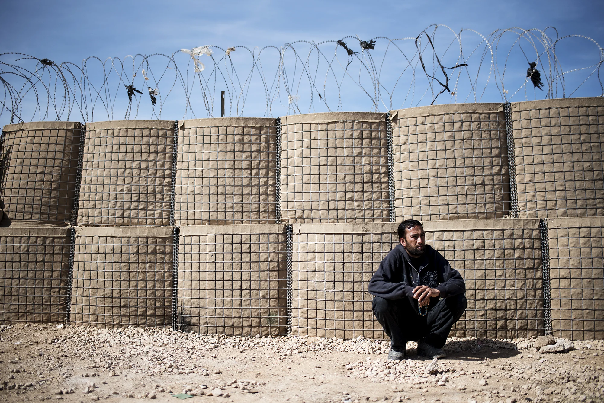 A man rests along a fence in Jordan's Zaatari refugee camp, some six miles from the country's northern city of Mafraq. February 2016.