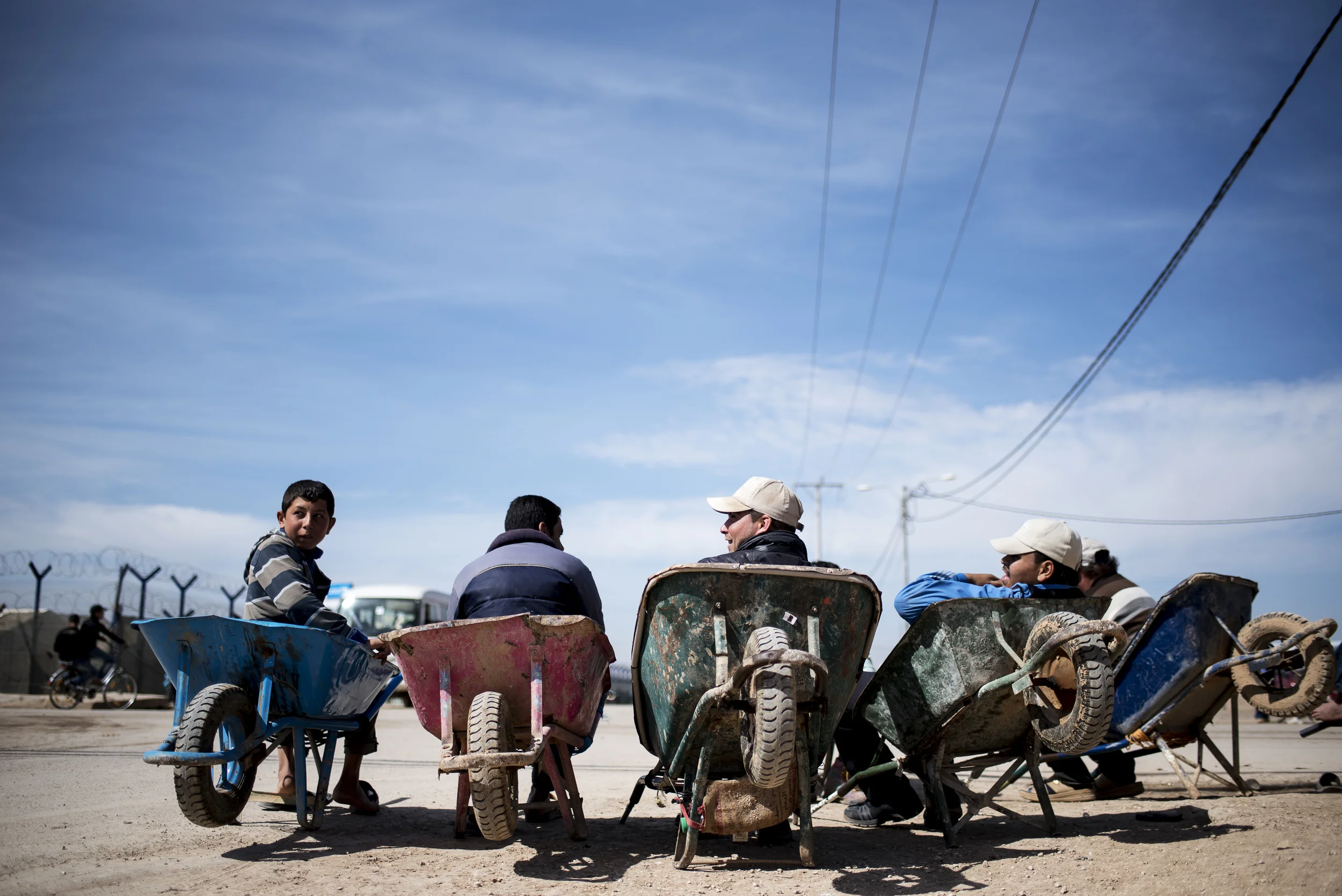 Syrian refugees sit on wheelbarrows at the entrance of Jordan's Zaatari refugee camp. The camp's population has swelled since small numbers of the refugees began fleeing to neighboring Jordan in 2012, with some 75,000 living there in 2015, according to UNHCR figures. February 2016.