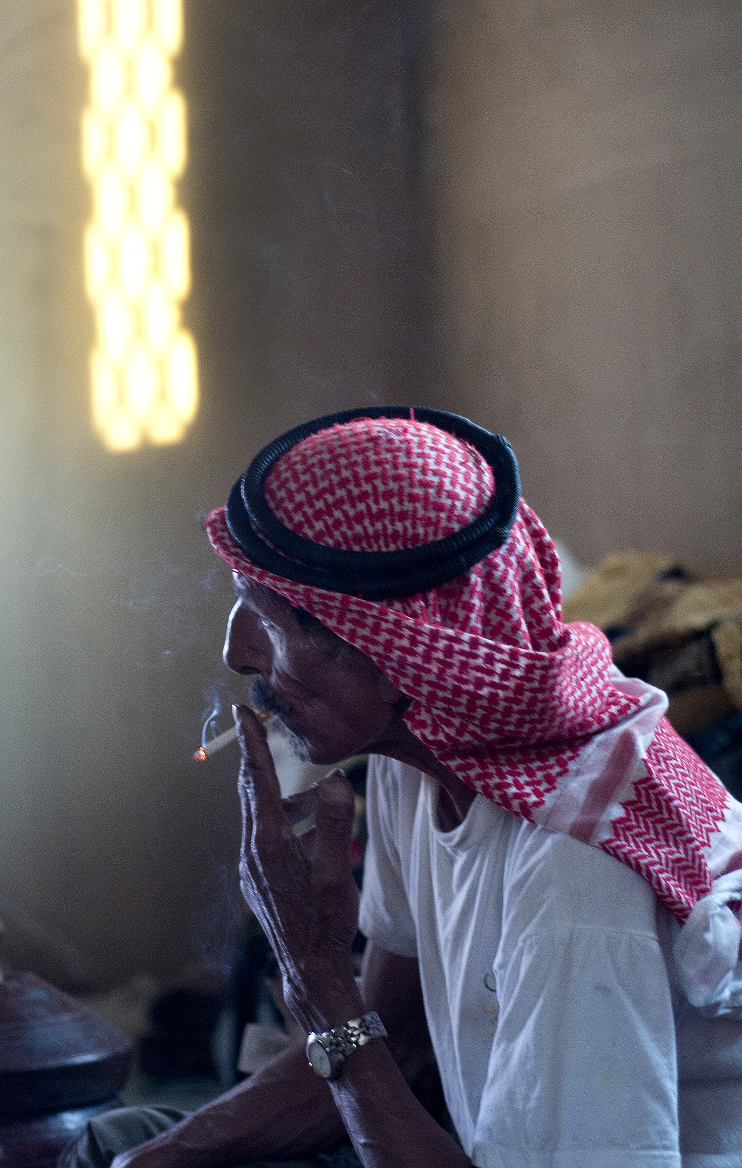 Bani Murra tribal elder Abu Hussain smokes a cigarette in his home in the outskirts of Amman. The tribe has broader roots in the Arabian Penninsula, where larger groups of Bani Murra began migrating in the early 1800s to settle throughout Jordan, Israel, Syria, Saudi Arabia and Egypt. July 2013.