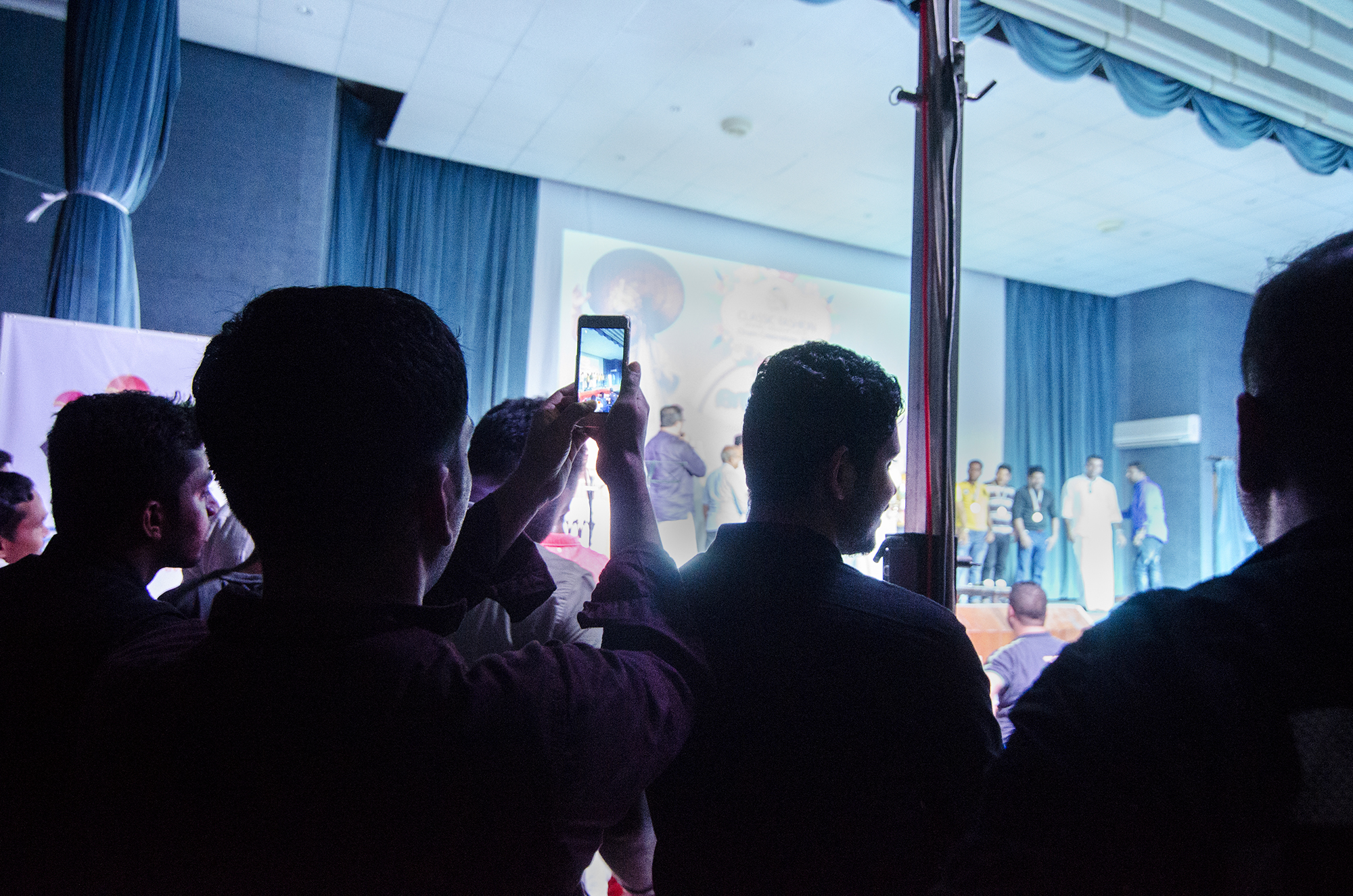 Audience members film performances from fellow garment workers.