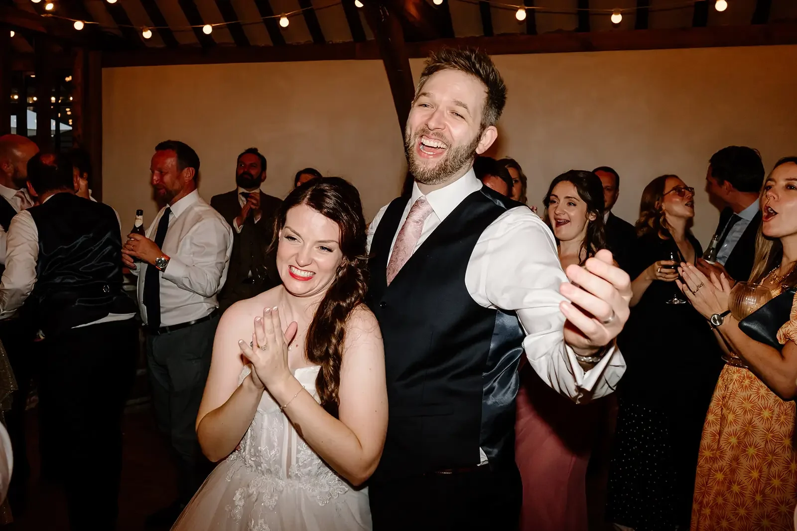 Joyful wedding reception with bride and groom dancing and guests enjoying celebration.