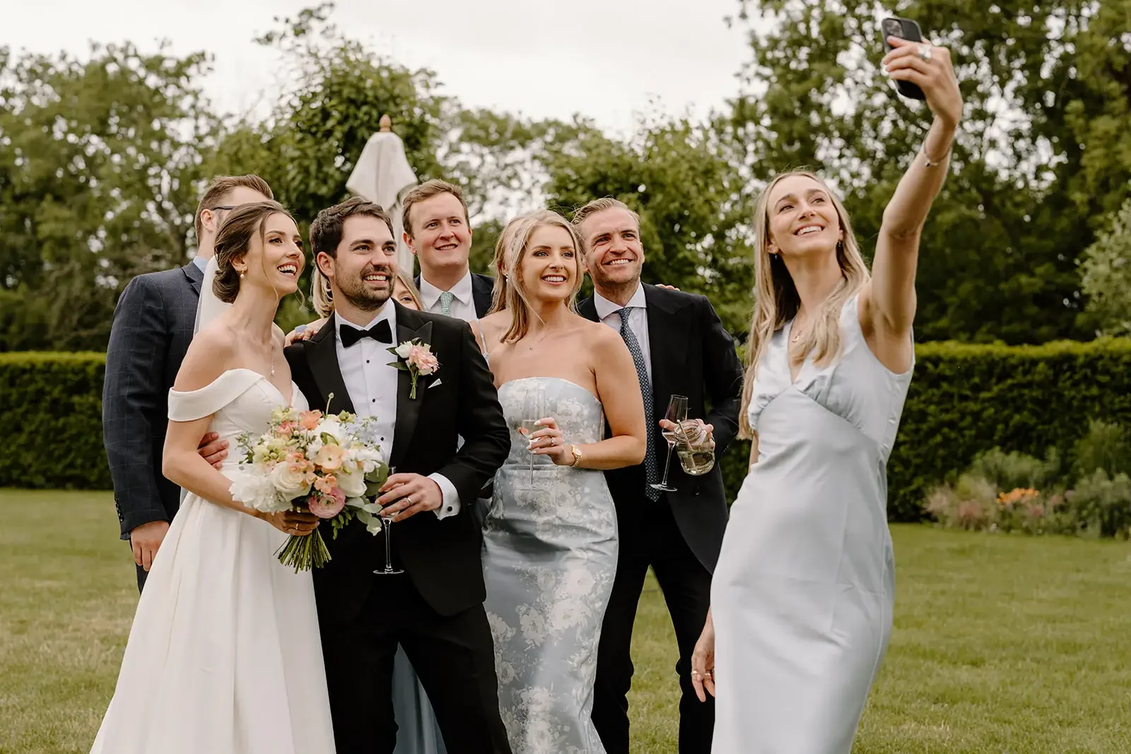 Group of people at a wedding taking a selfie outdoors
