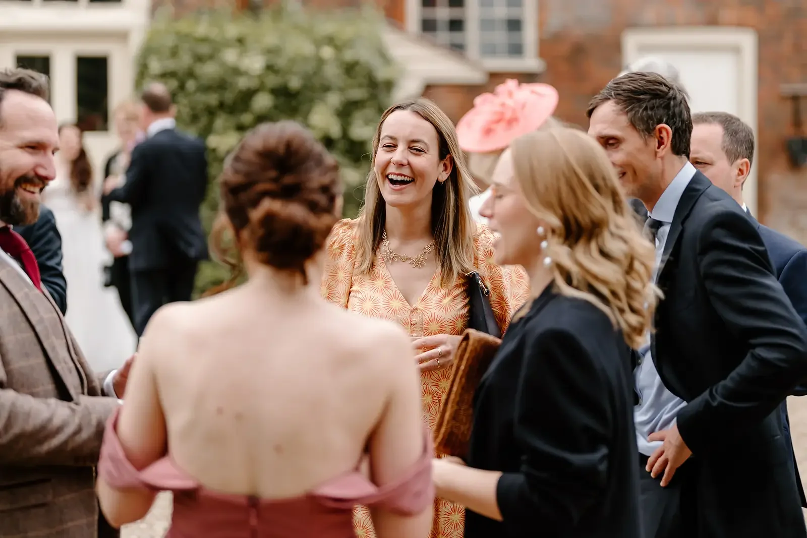 People dressed in formal and vintage clothing socializing outdoors at a garden party.