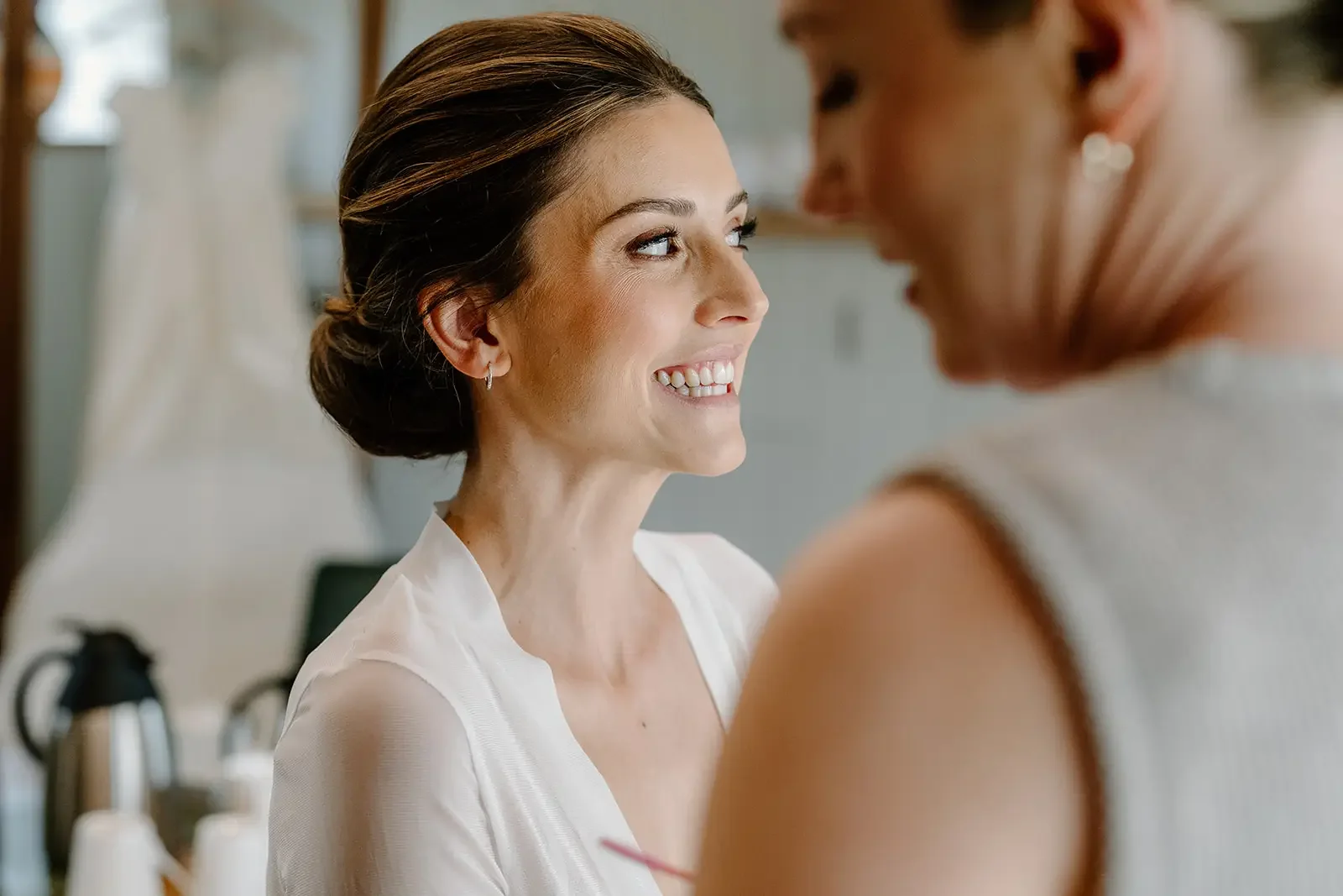 A woman smiling at another woman in a well-lit indoor setting.