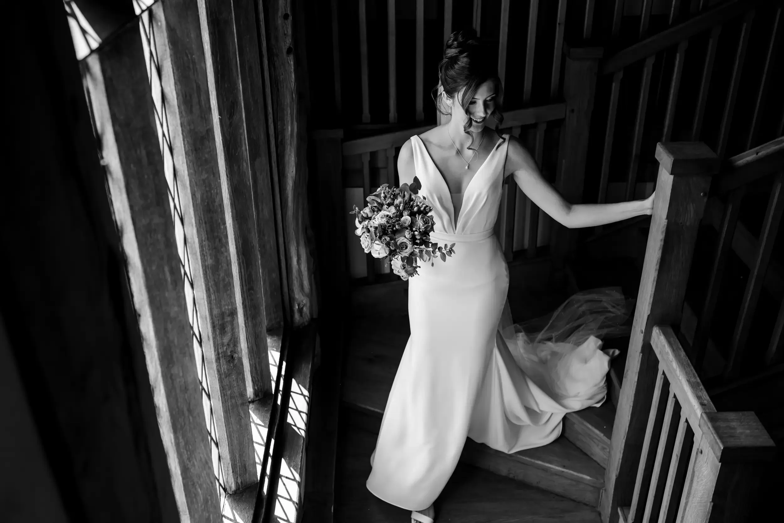 Black and white image of a bride walking down the stairs to her wedding ceremony at Cain Manor