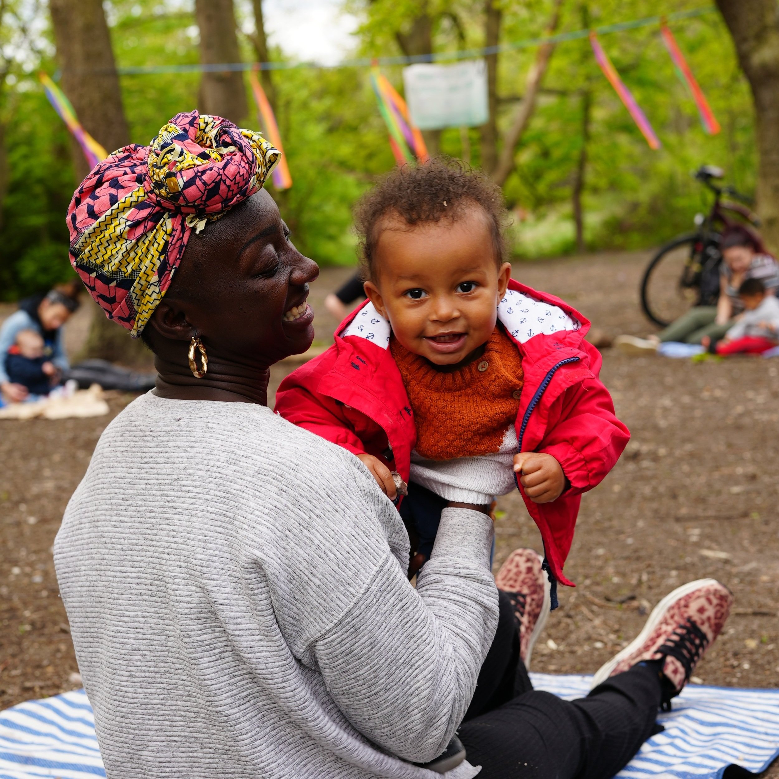  Mum is sitting with her back to camera a but is holding her little girl up to look over her shoulder at the camera 