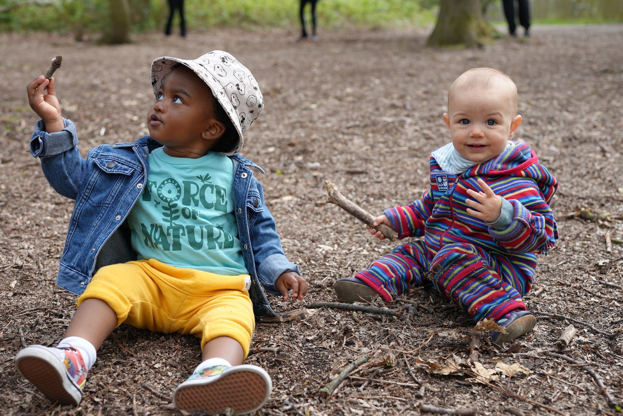  two little ones are sitting next to each other on the woods finding sticks for the activity 