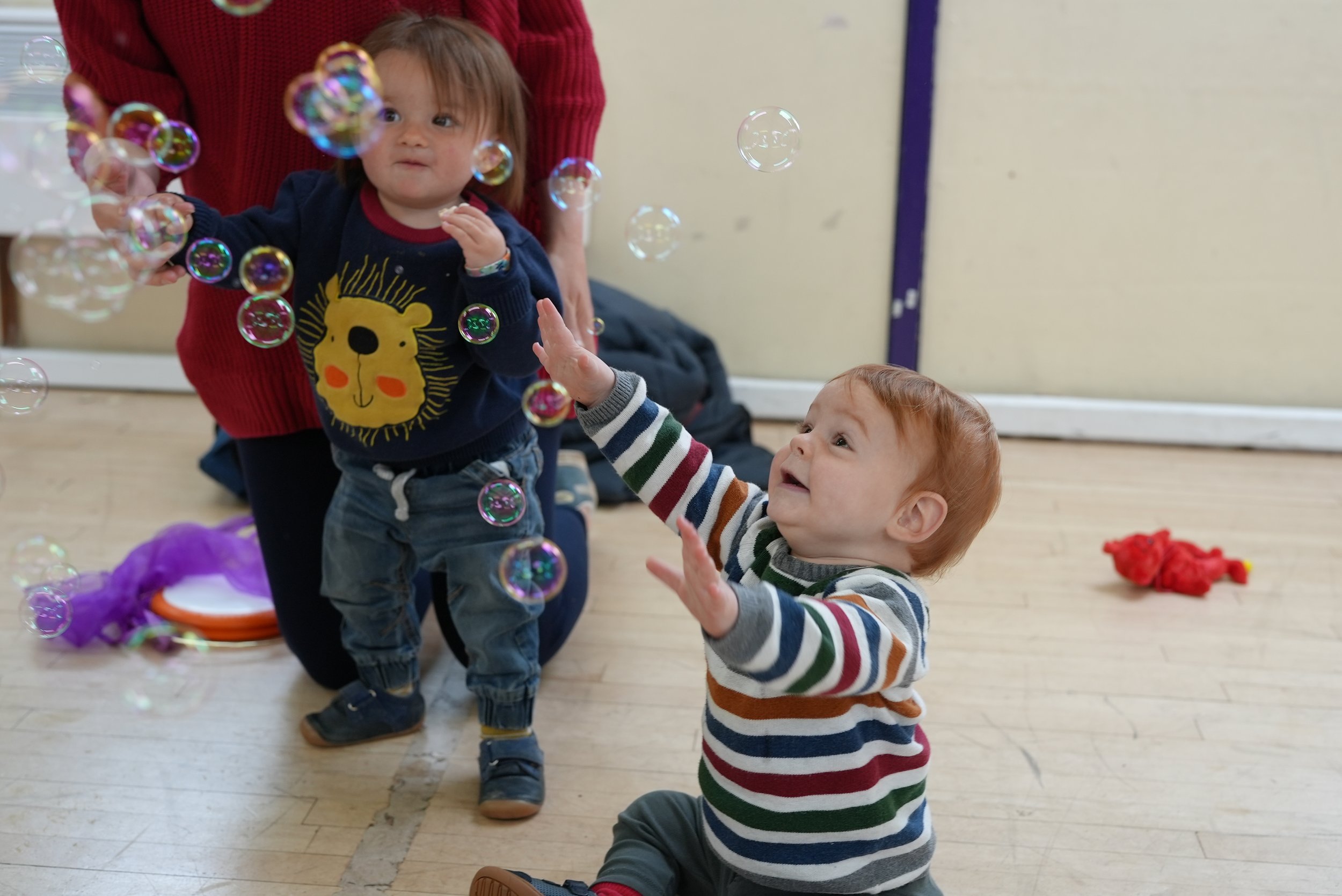  little boy is reaching up high trying to pop all the bubbles 