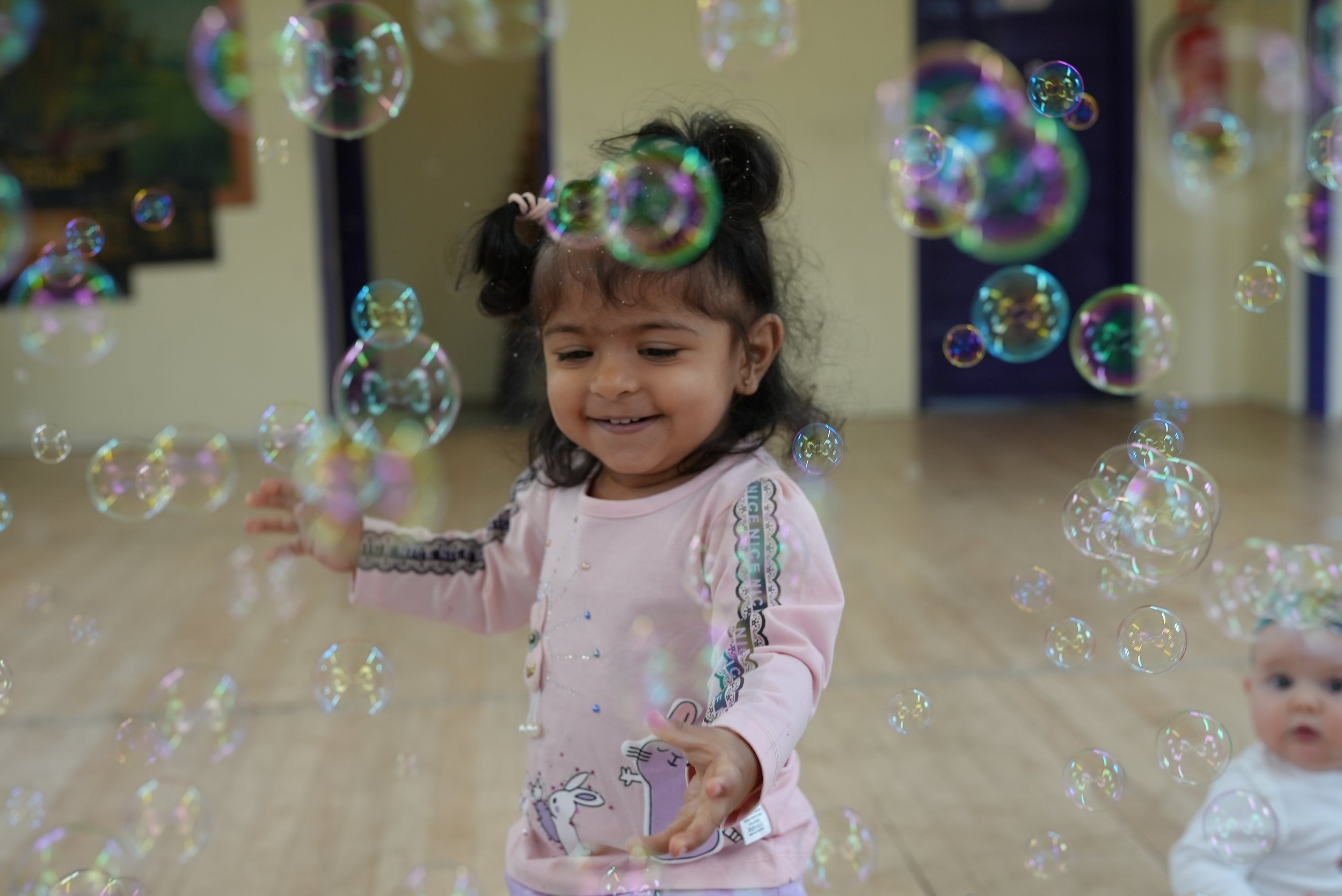  Lots of bubbles surround a big girl as she reaches out to pop them 