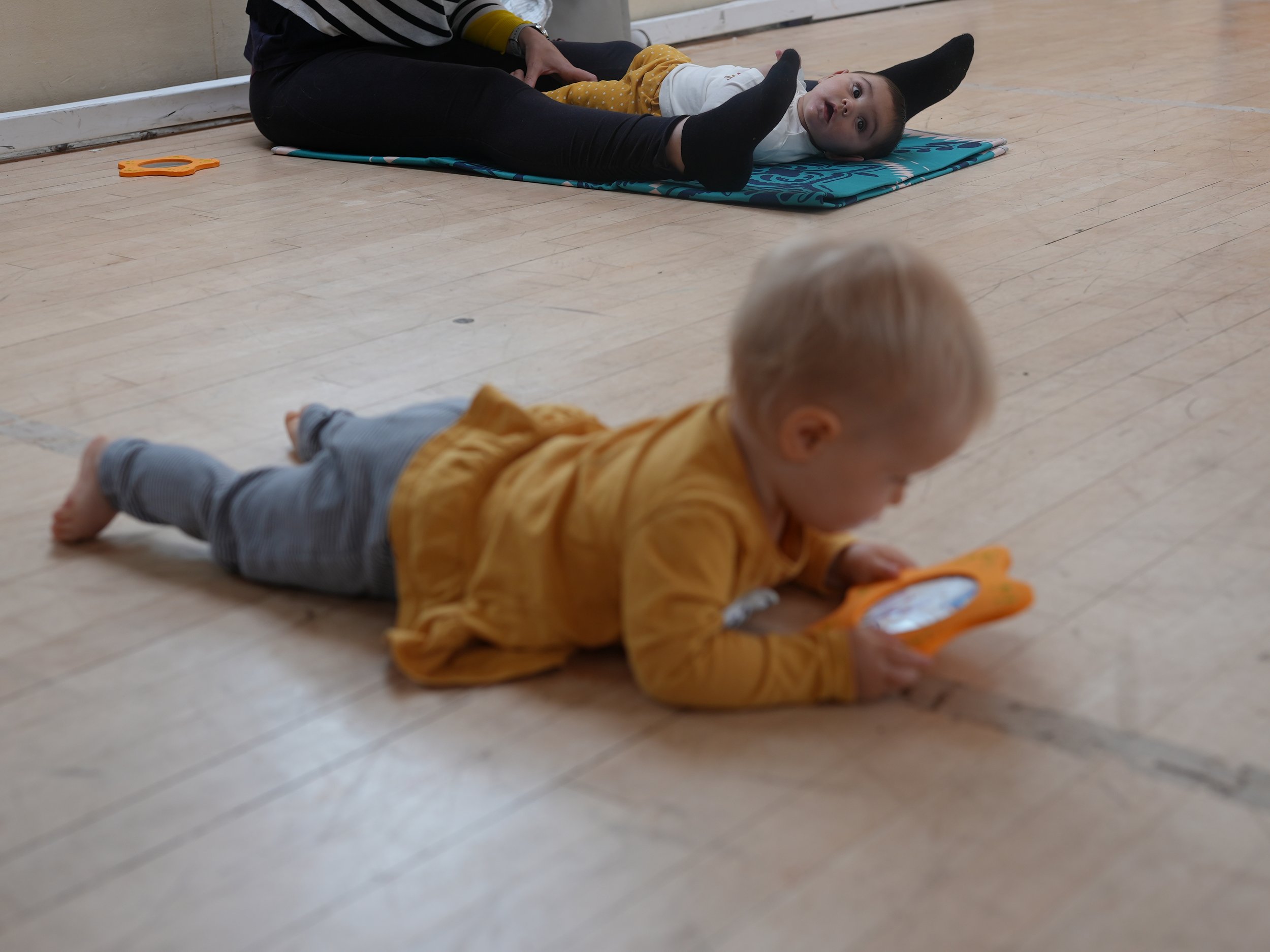  little girl is laying on the floor looking into her mirror 