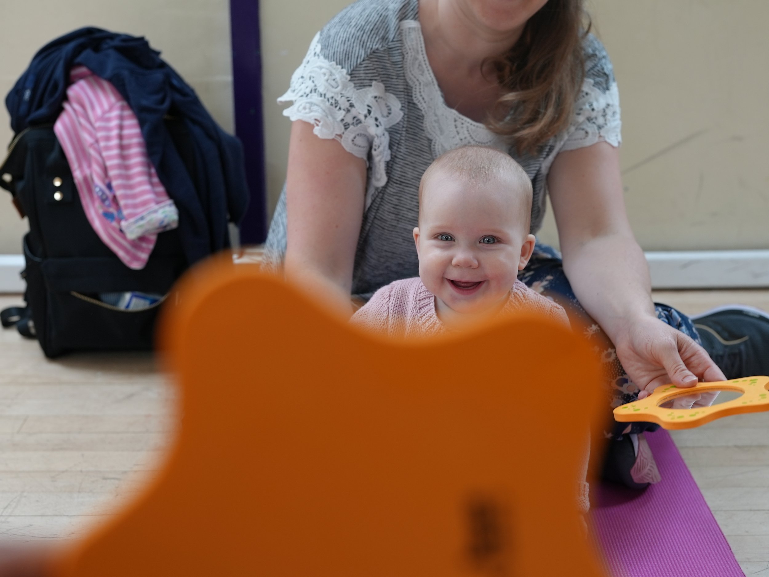  a mirror is being held in front of a little girl to look at. she is smiling at her reflection 