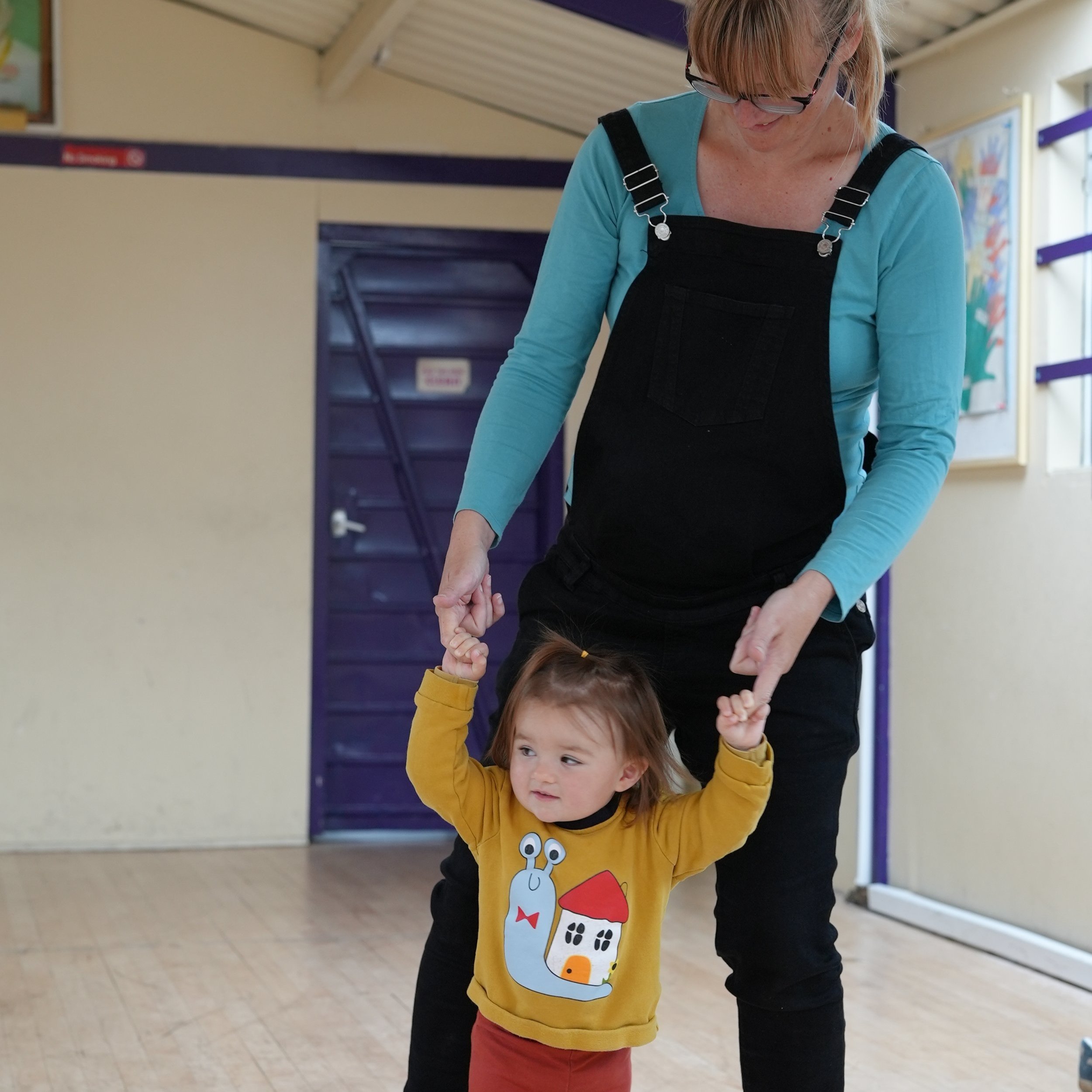  little girl and mum are standing up. holding hands and dancing 