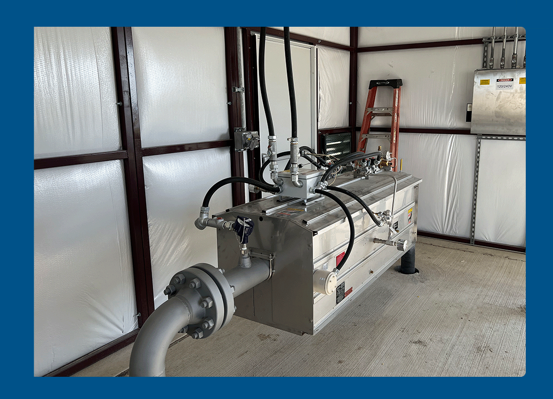 Industrial equipment with pipes and gauges inside a metal-framed building.