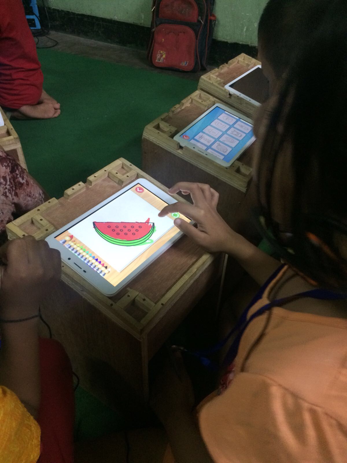 A young girl working with her tablet on a special desk, created by our Teach the World intern, Sunny.