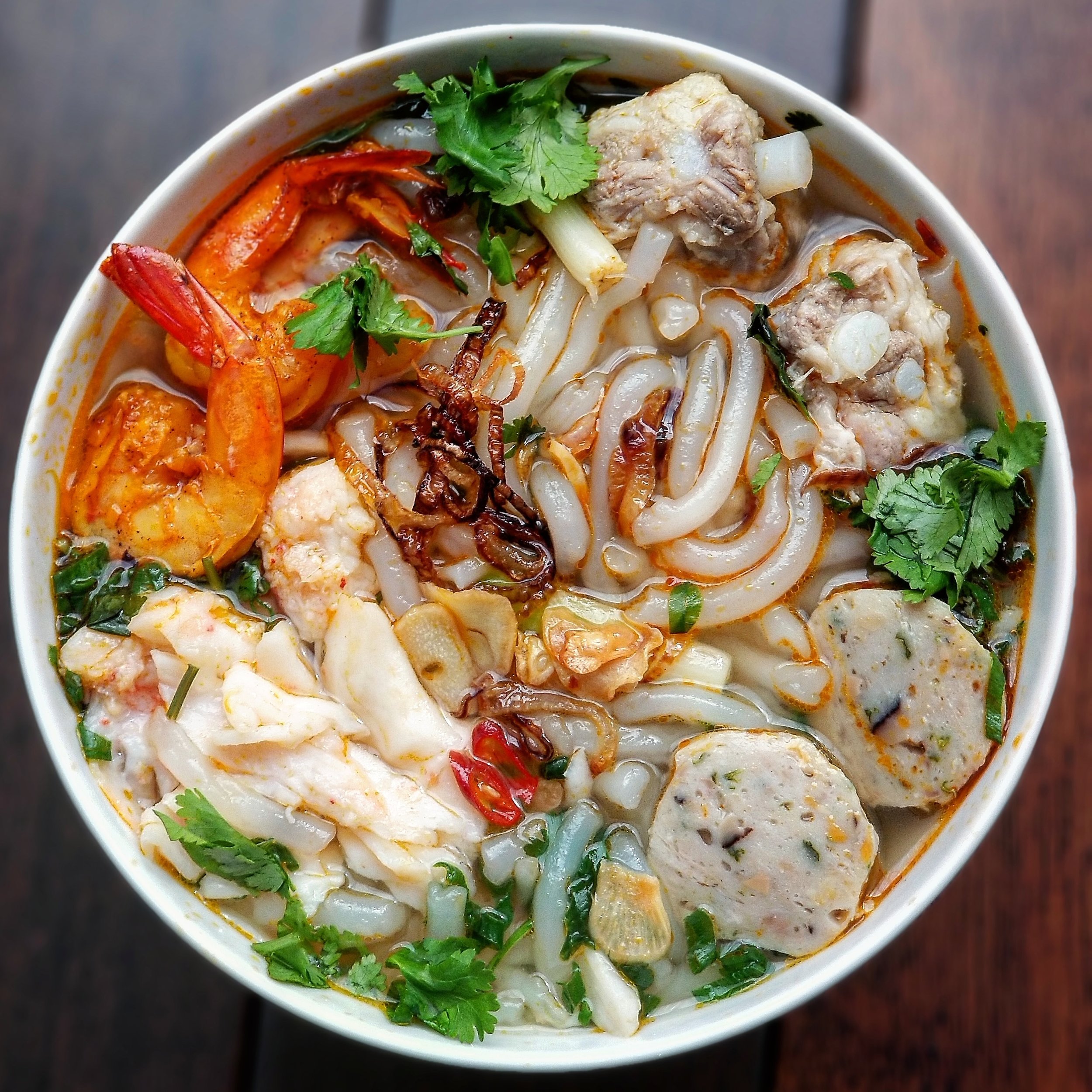 Bánh Canh Tôm Cua Chả Cá - Tapioca noodles in a pork and shrimp broth with shrimp, crab, fish cakes, fried garlic chips, fried shallots, scallion, cilantro and a bit of spicy saté chili paste