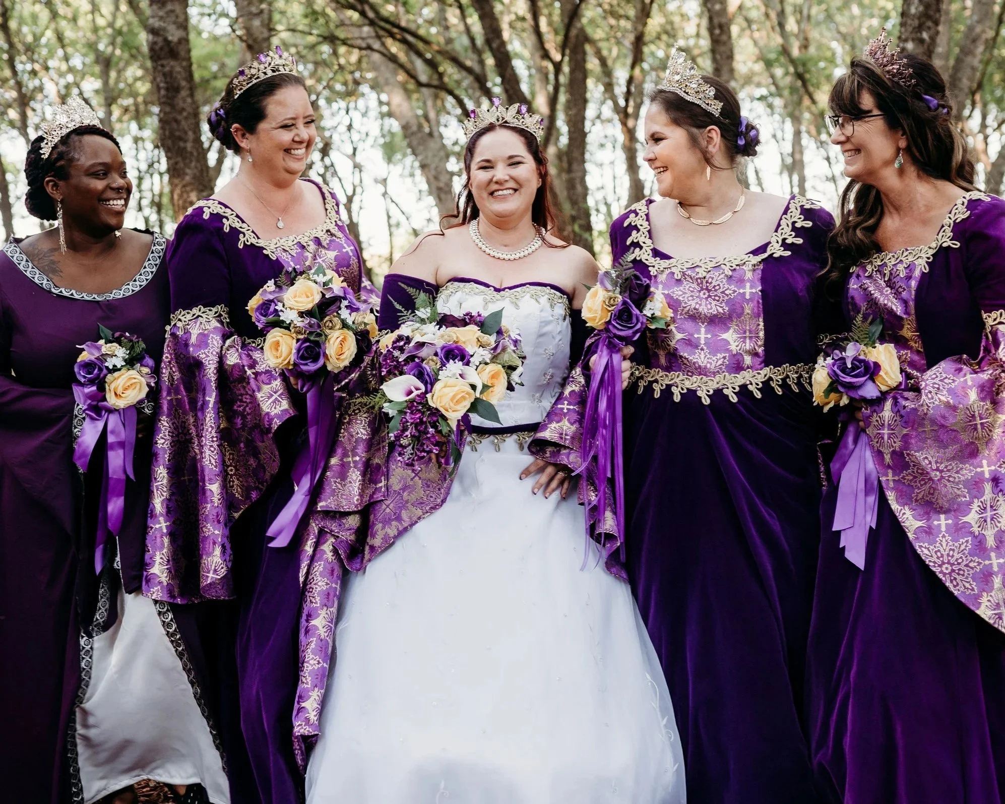 Renaissance‑style wedding party wearing regal gowns and jeweled crowns in a forest backdrop