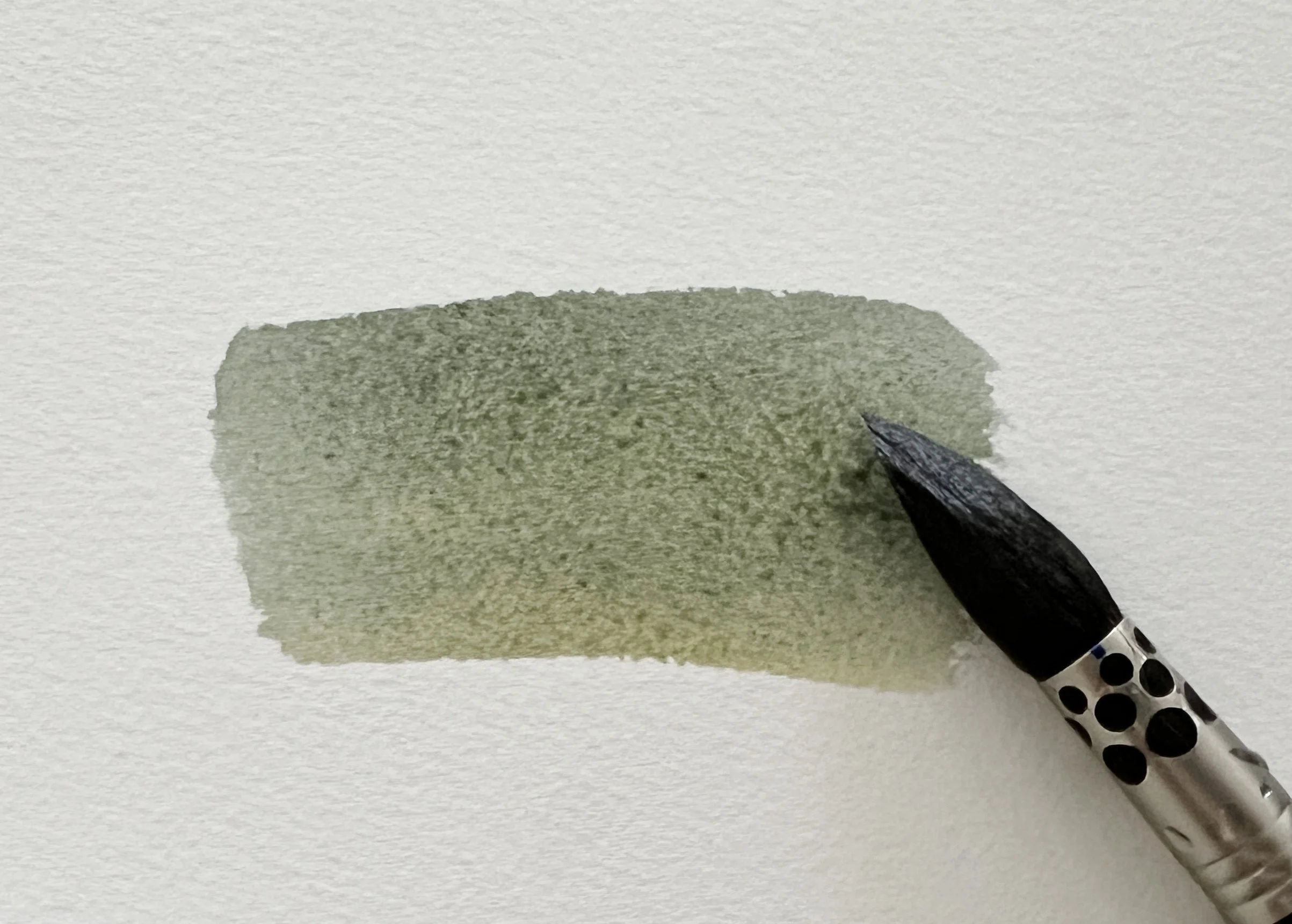 A watercolour mix swatch showing a soft, muted grey tone with visible granulation and brush texture.