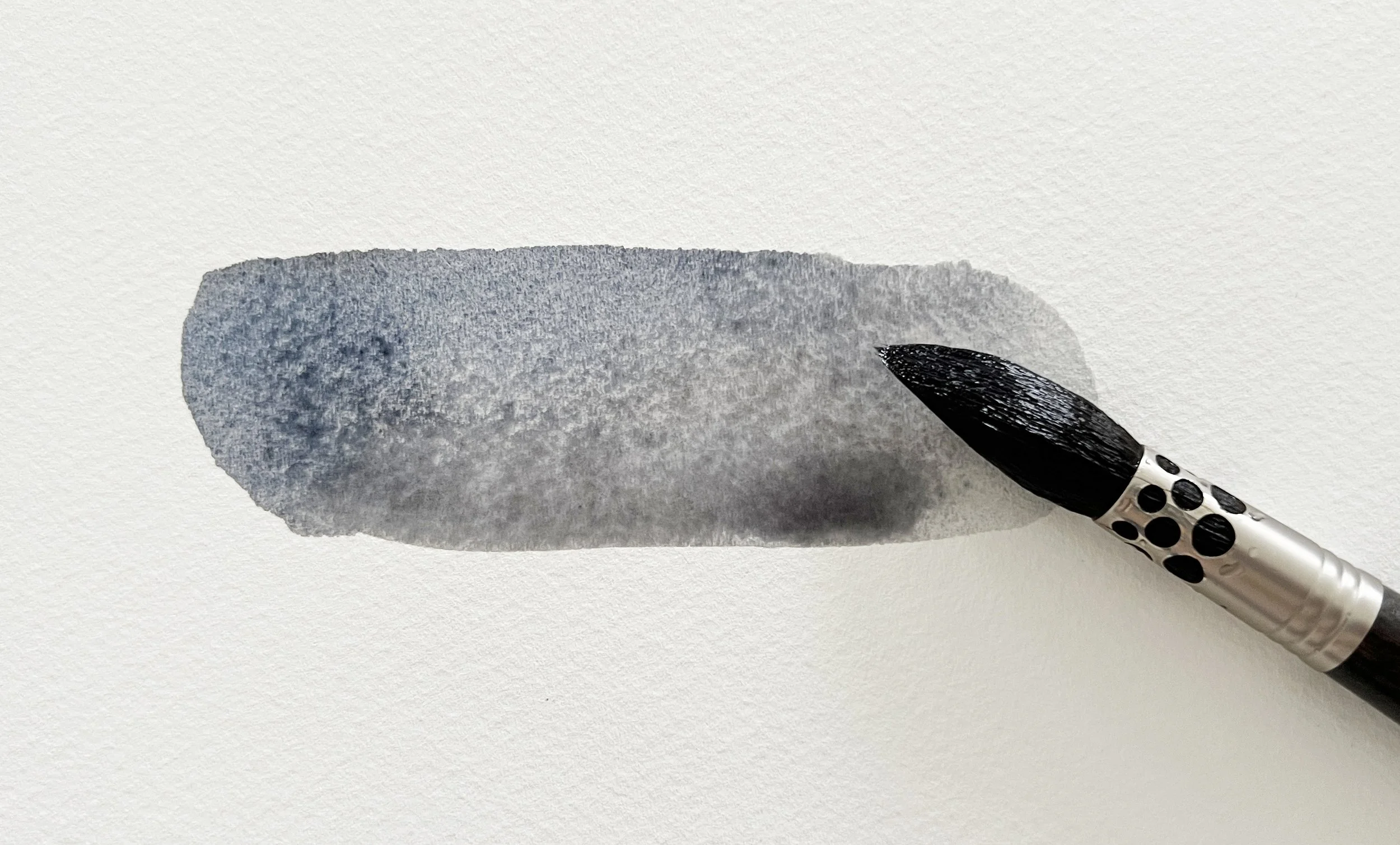 A flat wash of neutral grey watercolour paint created by mixing French Ultramarine and Burnt Sienna, applied with a round brush on cold press paper.