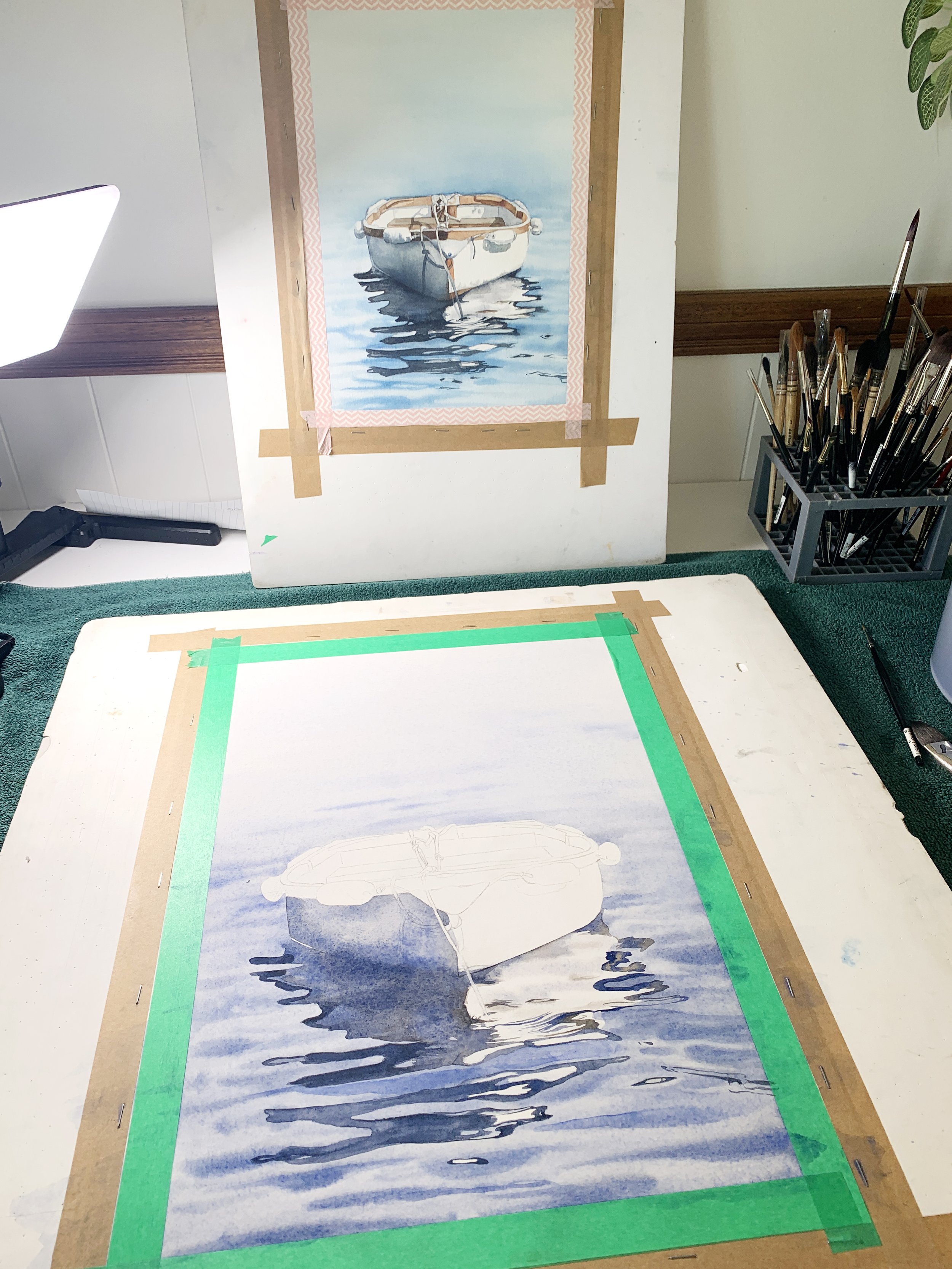 Watercolour boat in progress showing detailed reflections in the water, with reference painting in the background.