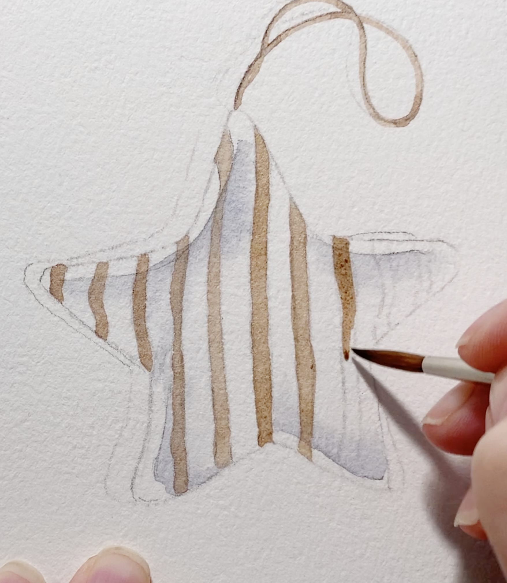 Watercolour star ornament with brown vertical stripes being painted carefully with a fine round brush over a soft grey base layer.