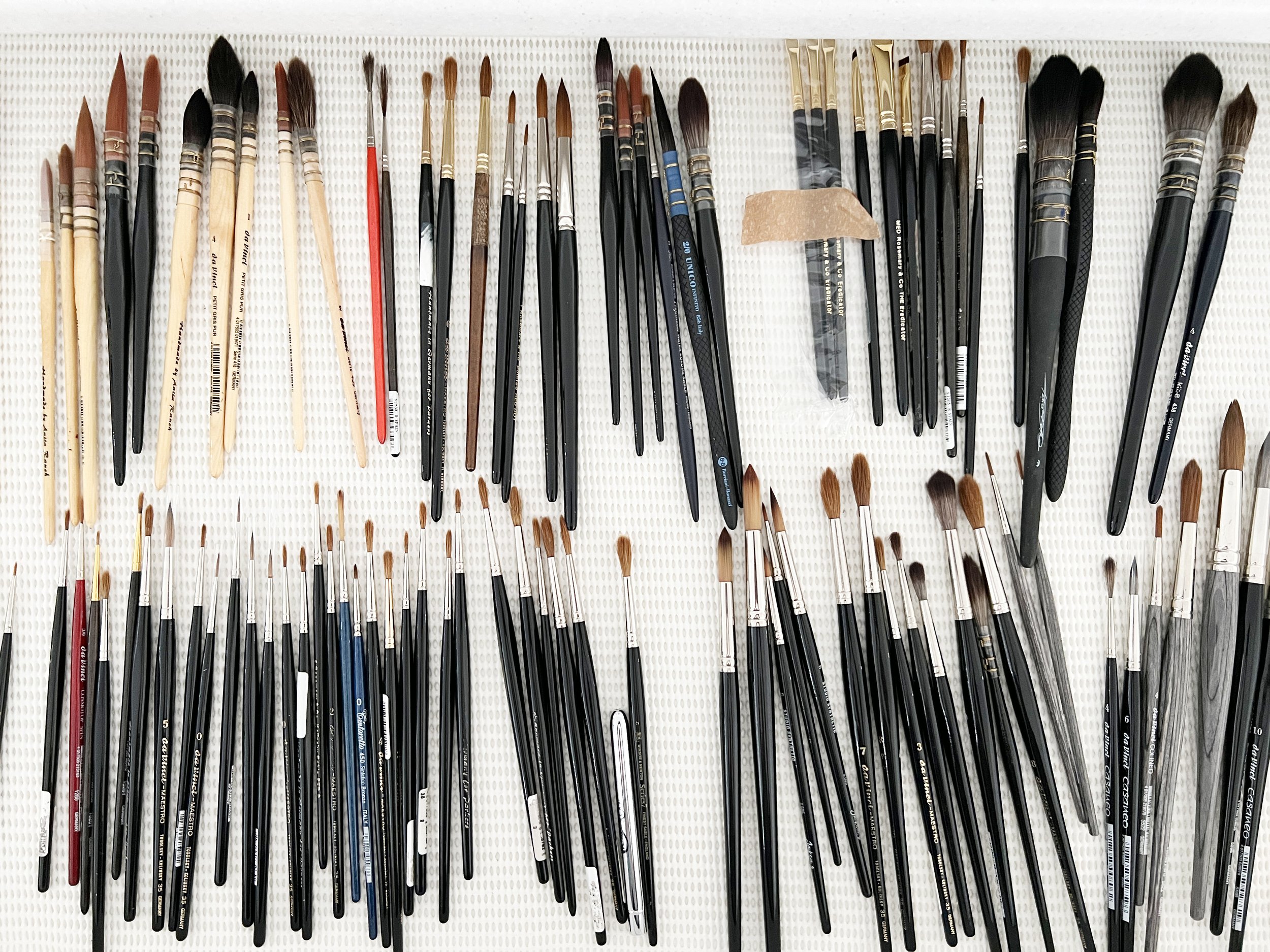 Collection of assorted watercolour brushes, including rounds, flats, and mops, laid out in an organised drawer.