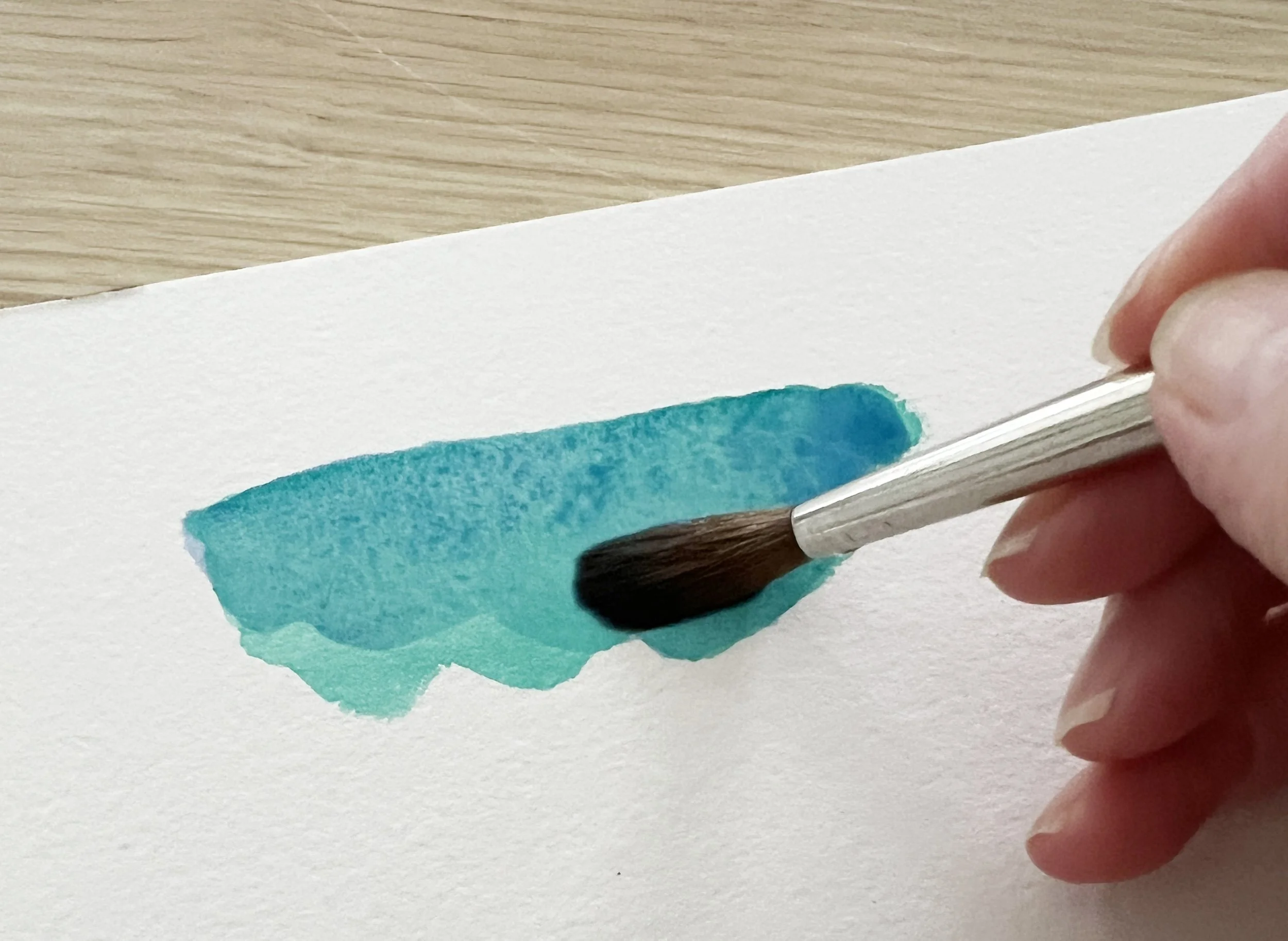 Close-up of wet-on-wet green watercolour wash showing pigment movement and soft blended edges.