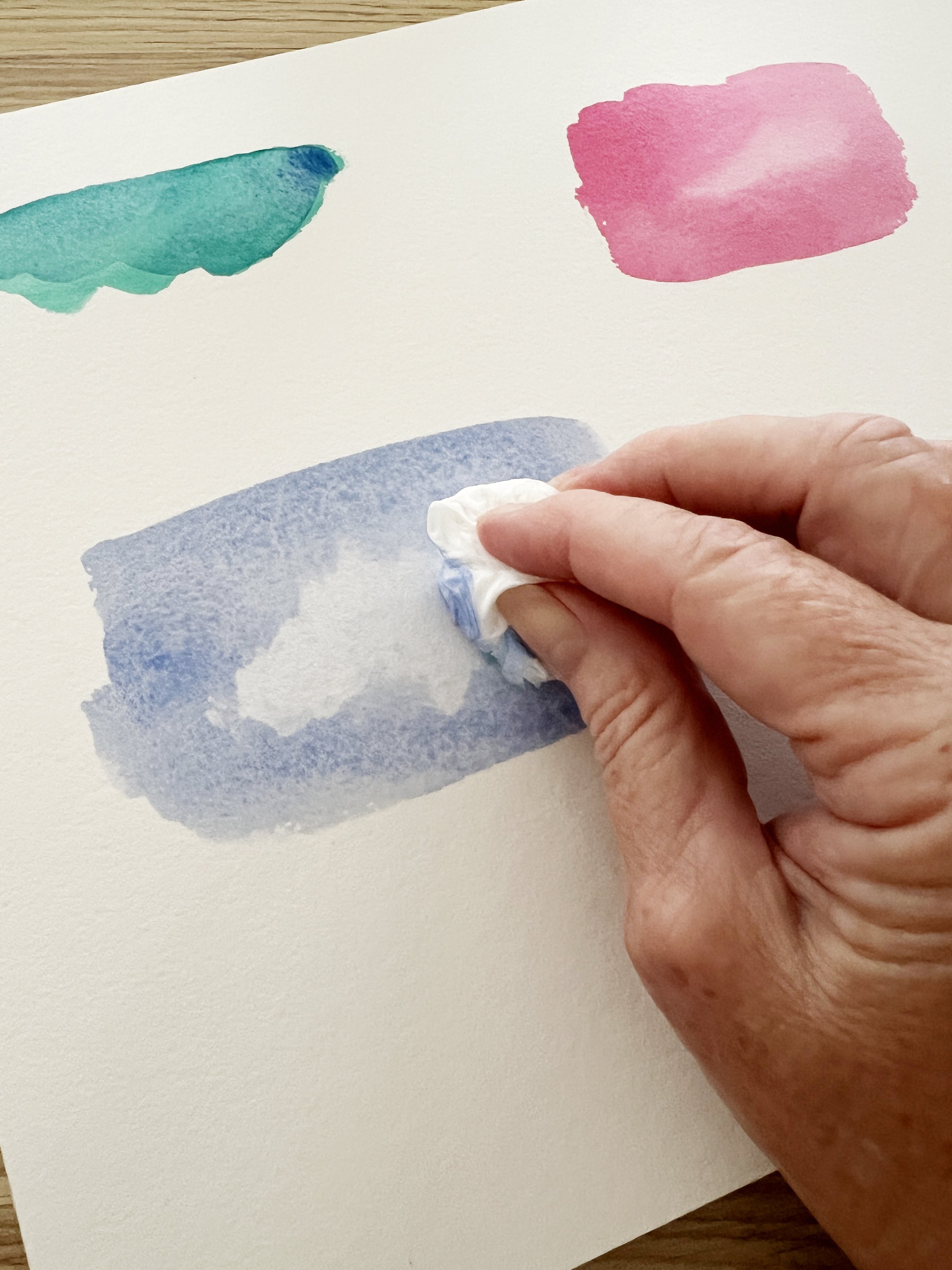 Lifting watercolour paint with tissue to create soft highlights and adjust values in a blue wash.