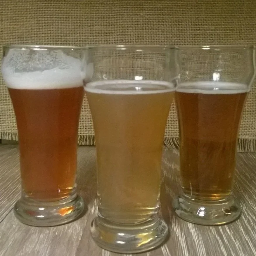 Three small glasses of beer, one copper, one straw, and one golden