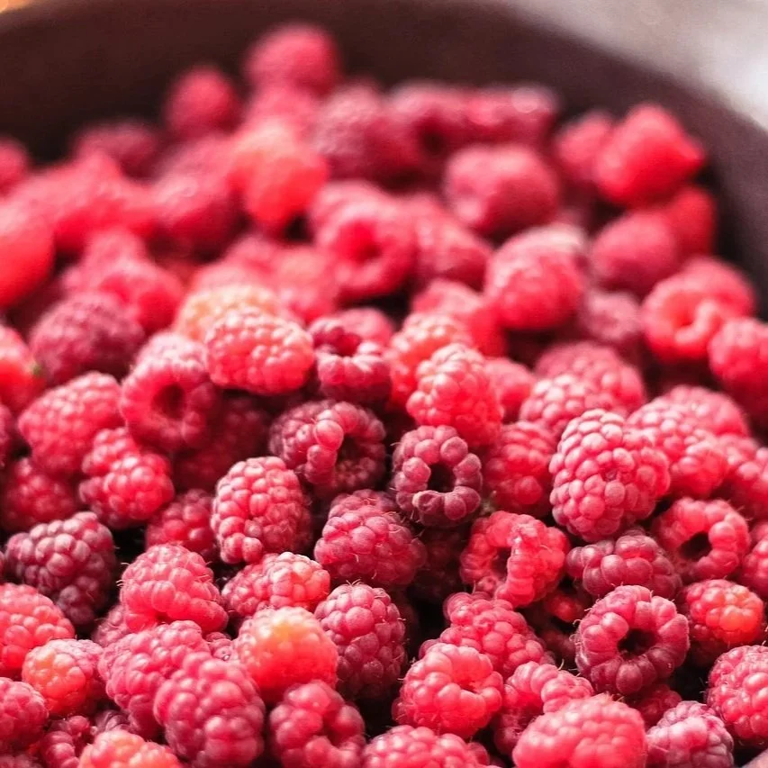 Close up of red raspberries in a dark serving bowl
