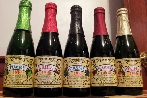 Lindemann's Pomme Lambic bottle with green foil top, Lindemann's Kriek with red foil top, Lindemann's Cassis with black foil top, Lindemann's Framboise with burgundy foil top, Lindemann's Peche with gold foil top