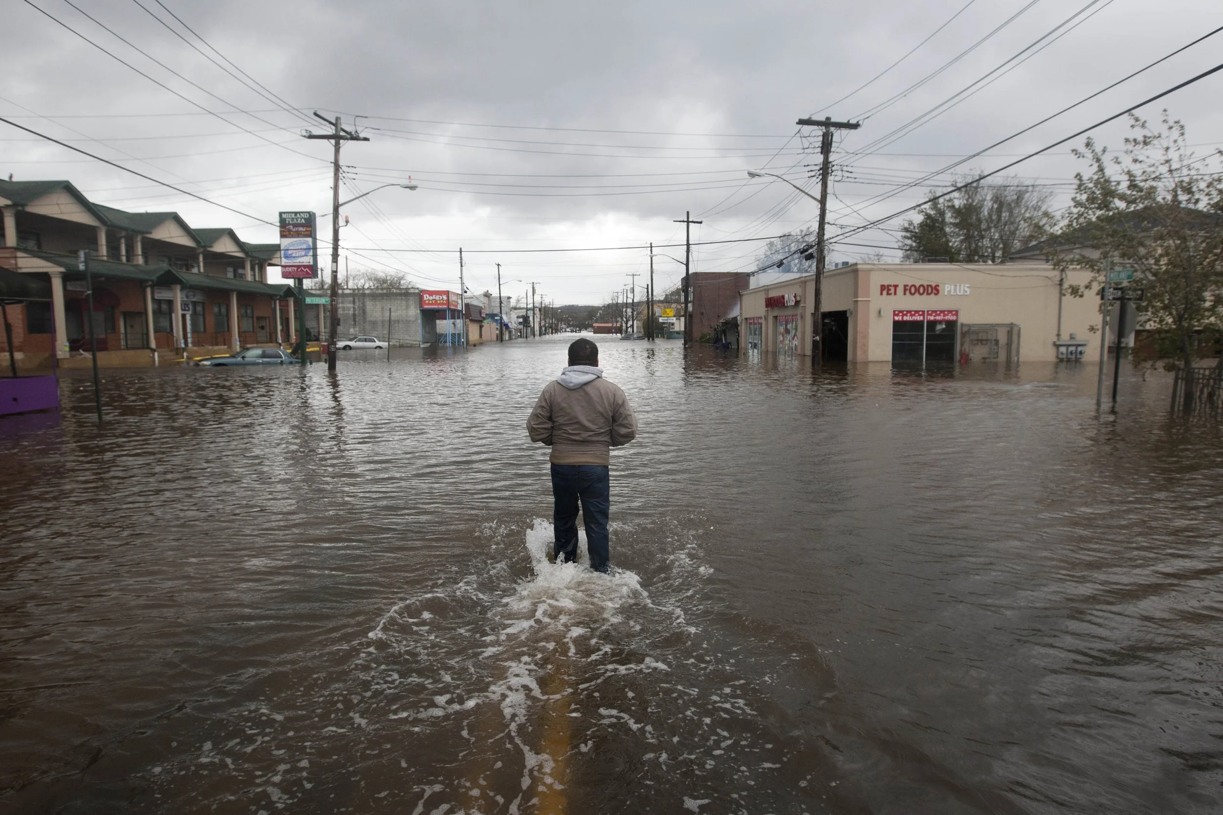  A man walks into the flood waters on Midland Avenue to look for his brother Tuesday, Oct. 30, 2012, in the Midland Beach neighborhood of Staten Island, N.Y. Hurricane Sandy made landfall late Monday devastating the island's East Shore and leaving hu