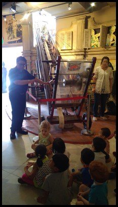  The officer showing the children the ladder which firefighters used in the past. 