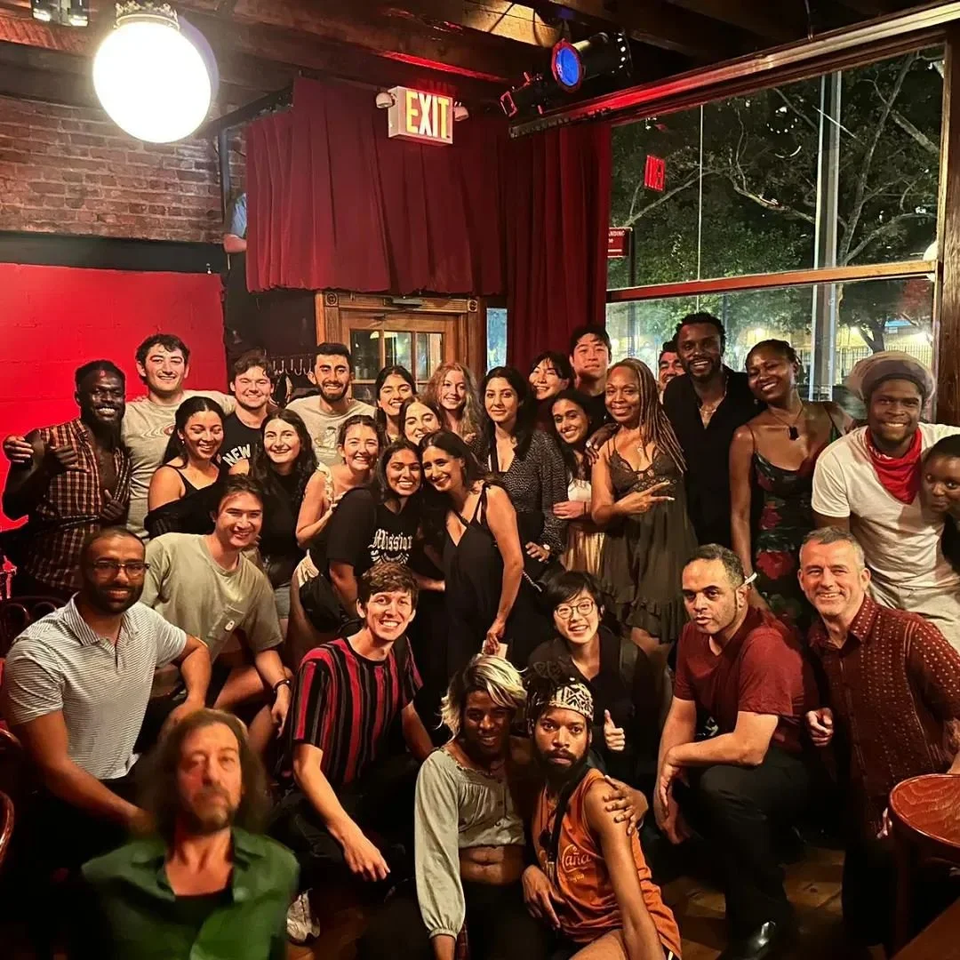 A large group of diverse people gathered together in a lively indoor setting, smiling for a group photo.