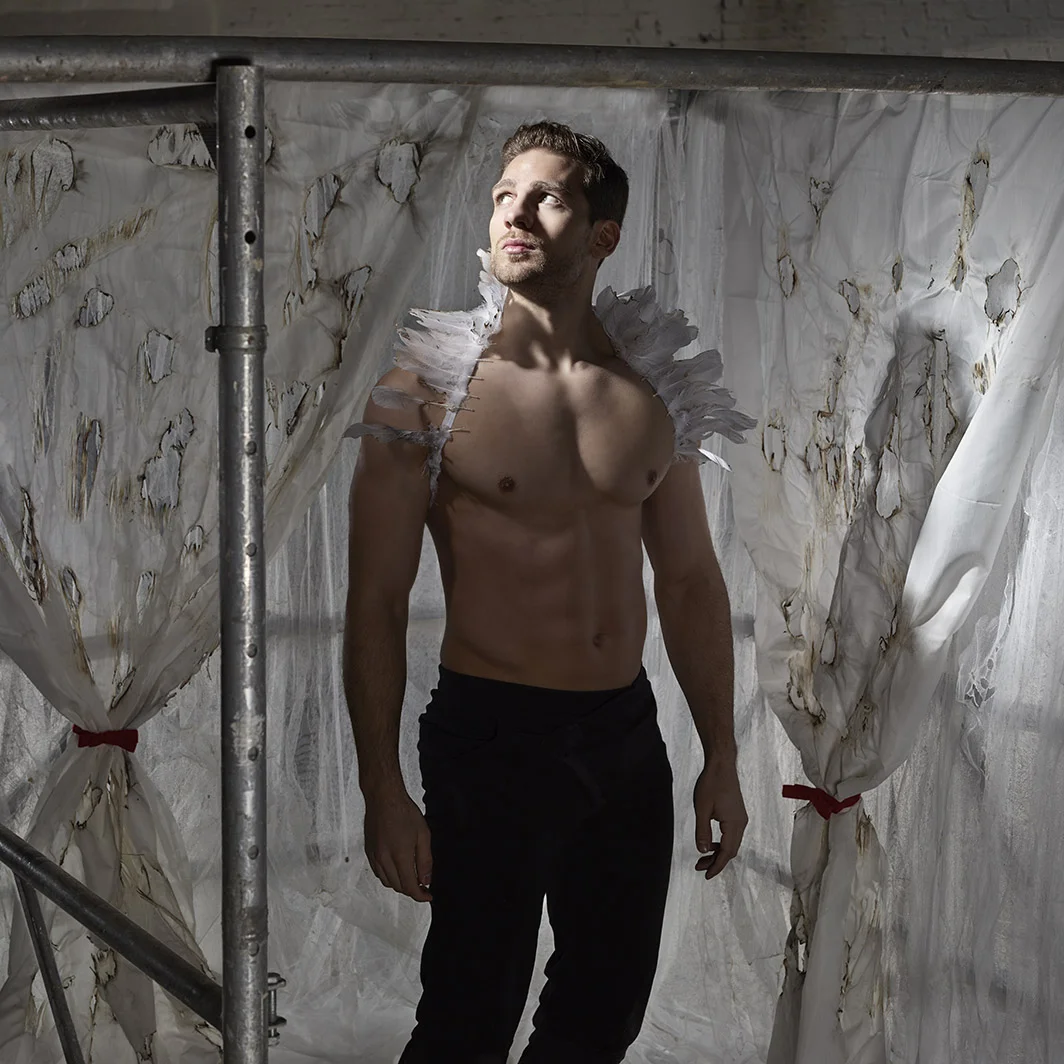 Tesseract man wearing wings standing in burnt curtains