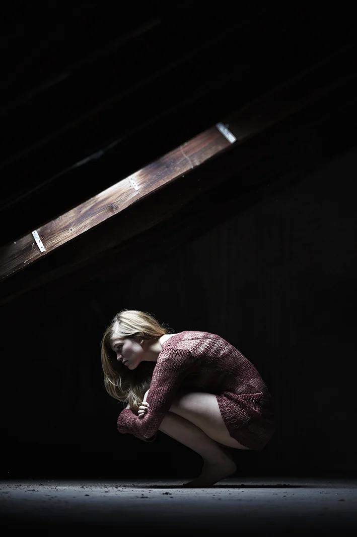 Portrait-Frau-hockt-unter-Dachfenster