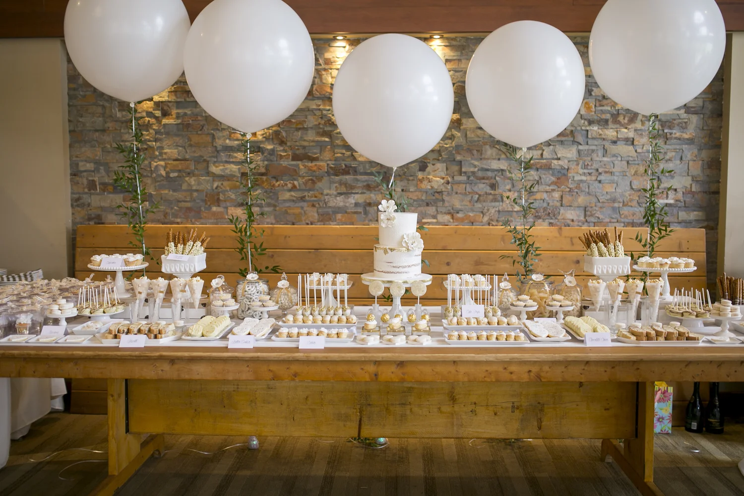 White wedding cake and dessert table with oversized balloons