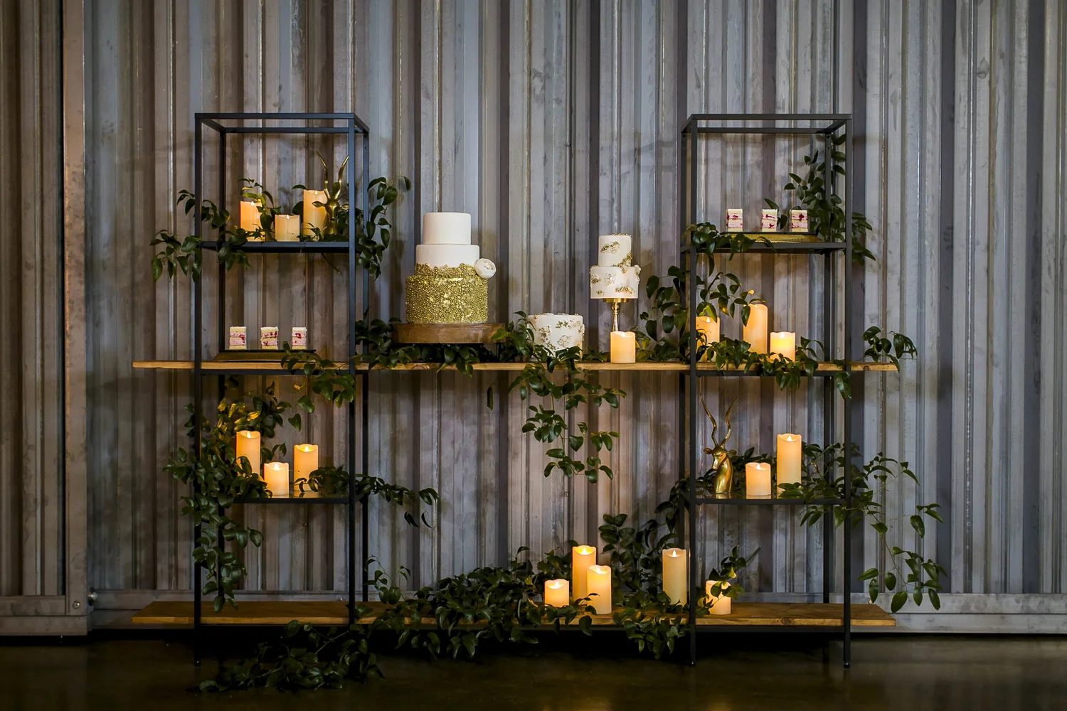 Modern wedding cake display with greenery and candles