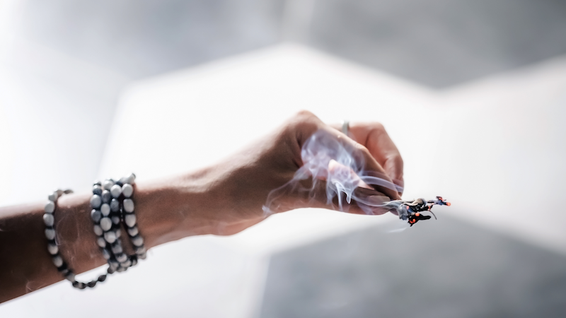 A photo of someone burning sage as an example of how to cleanse your love stones and crystals prior to using them for manifestation.