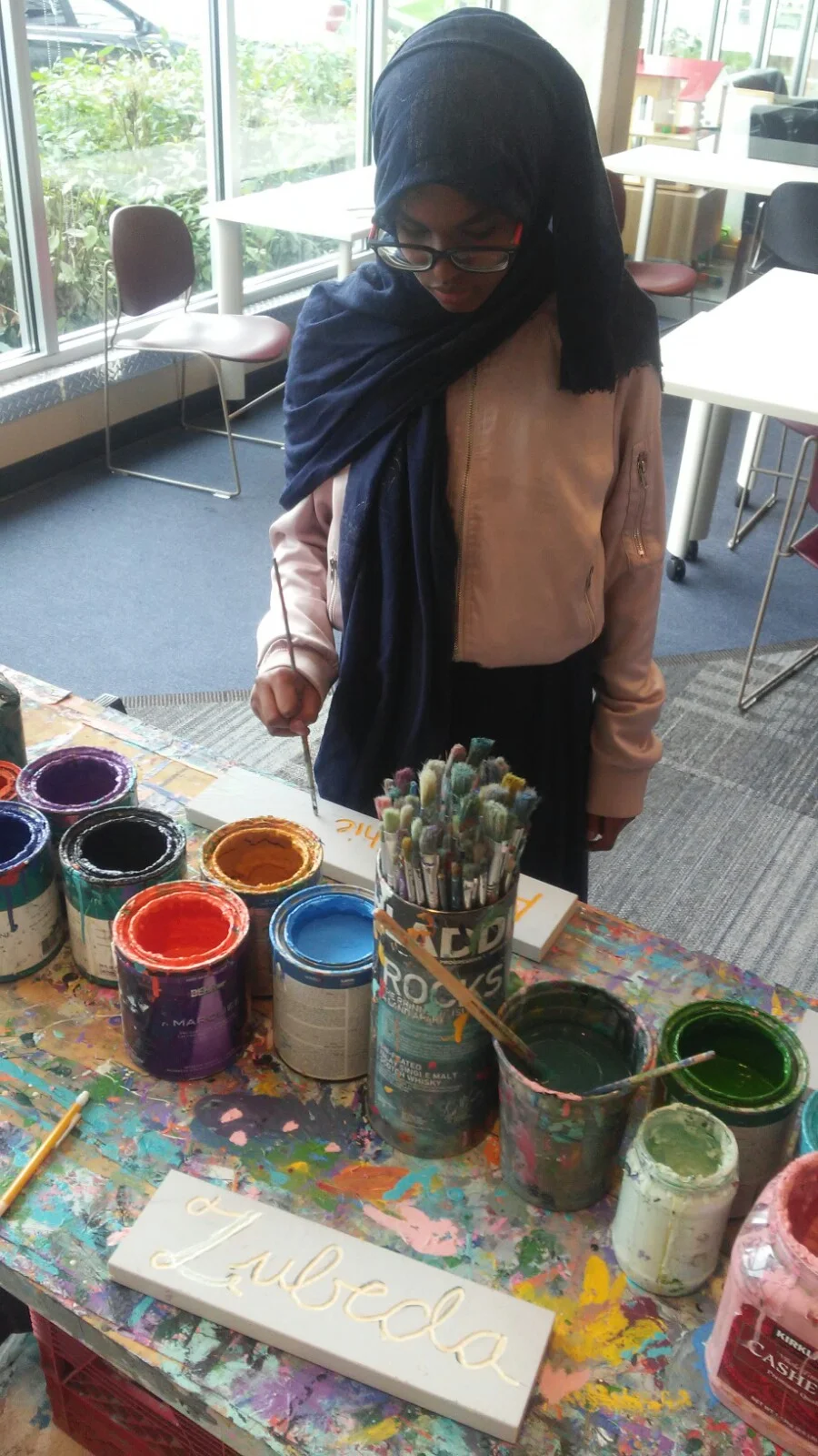 Aisha joins the Teen Tech Squad to work on sign painting led by Peter Thompson in coordination with Springboard for the Arts.