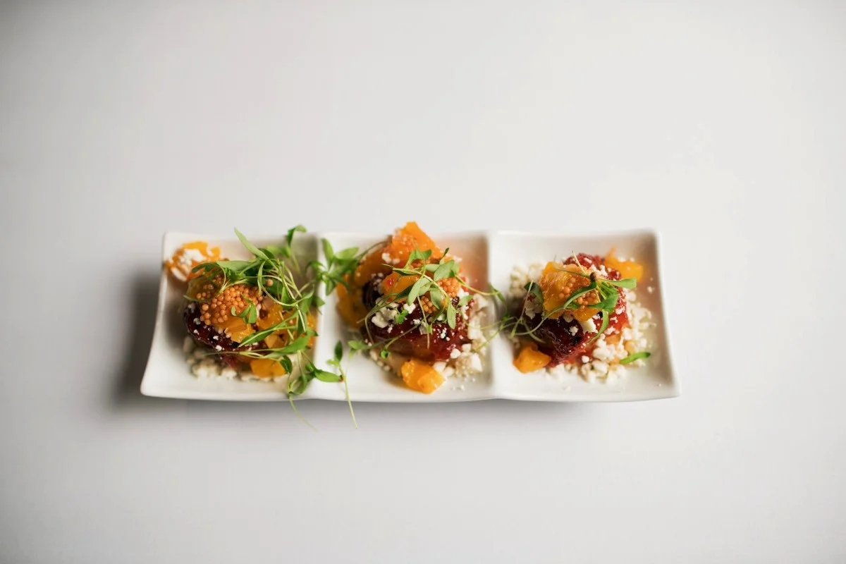 Gourmet dish with microgreens, cheese, and colorful toppings on a white plate