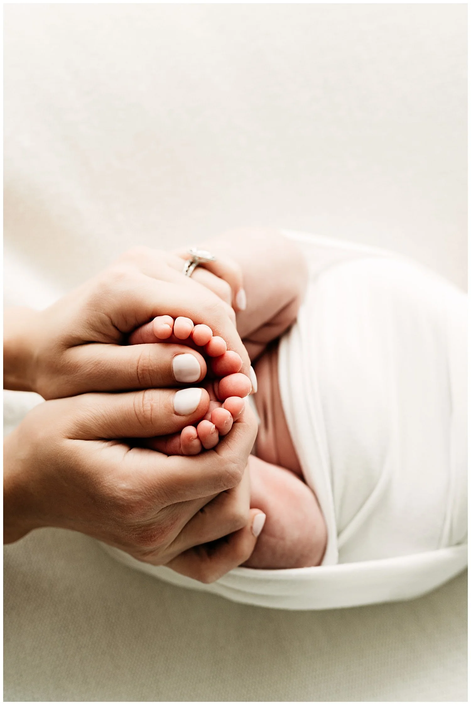 A photo depicting a mothers hands delicately holding her newborn baby's feet.