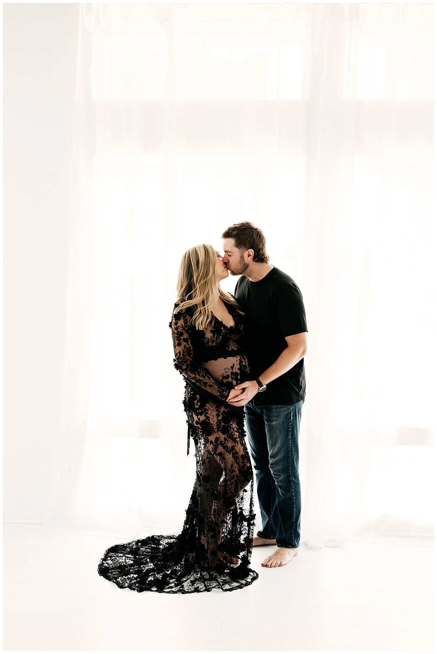 A photo of an expecting couple in a loving embrace, complete with a kiss.
