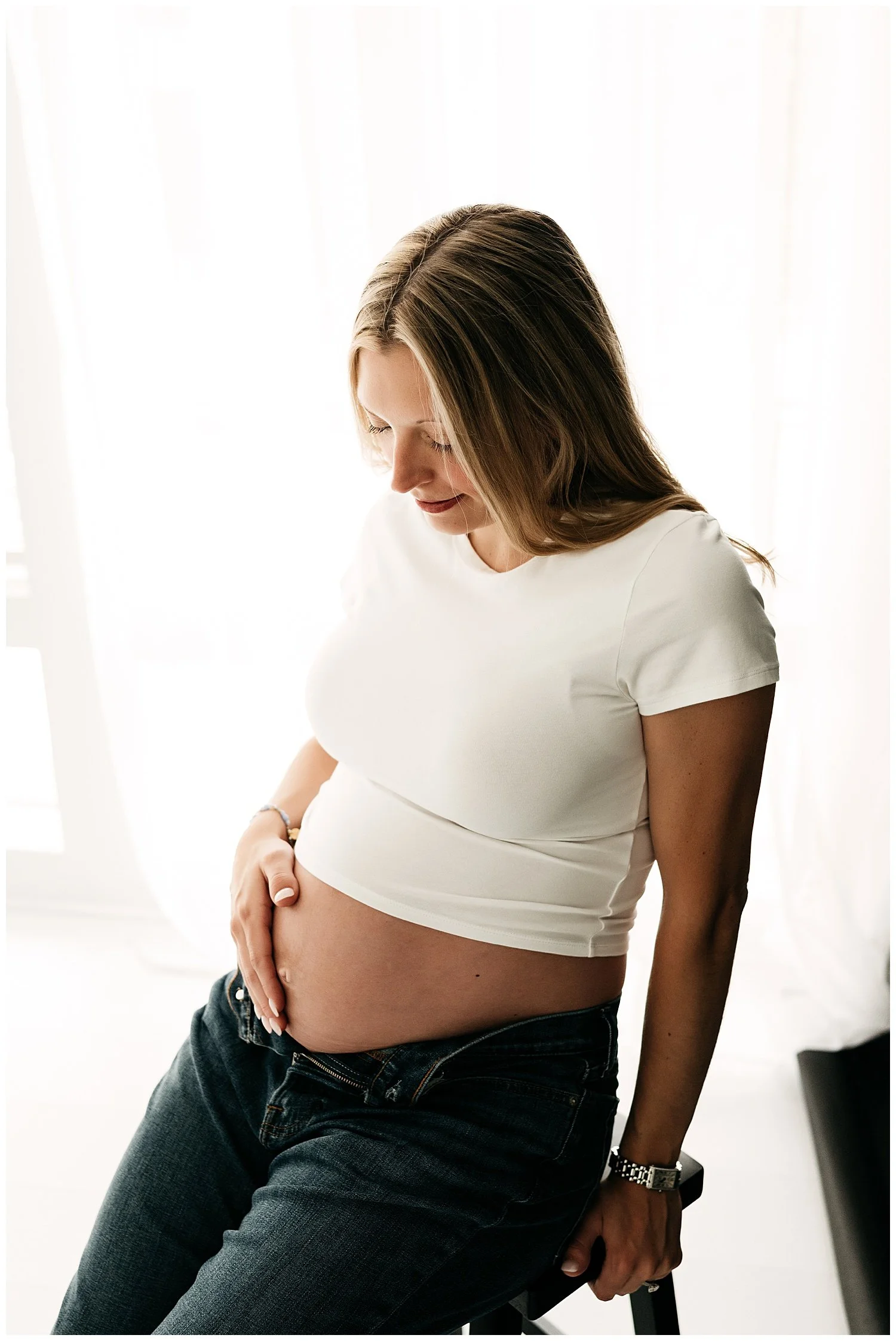 An image of an expectant mother cradling her belly, angled down from above.